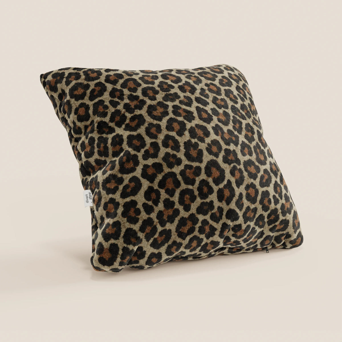 Il cuscino Wild della collezione Wild di divitt.sbs è un cuscino quadrato in microfibra lavabile in lavatrice con una vistosa stampa leopardata marrone, nera e marrone chiaro su beige chiaro e una piccola etichetta laterale bianca.