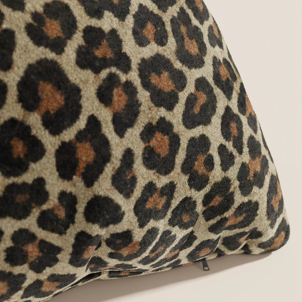 Primo piano del cuscino Wild della collezione Wild di divitt.sbs: un cuscino in microfibra impermeabile con stampa leopardata a macchie nere e marrone scuro su tinta unita, caratterizzato da una piccola cerniera nera sul bordo inferiore.