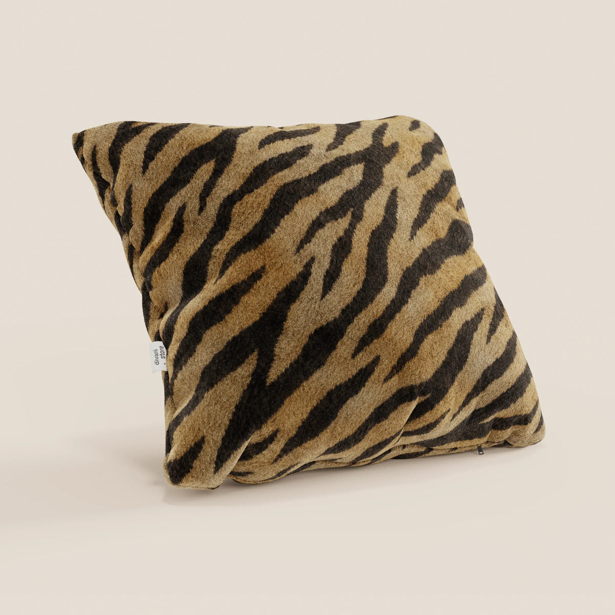 Il cuscino Wild della collezione Wild di divitt.sbs è un cuscino quadrato in microfibra impermeabile con un morbido motivo a strisce di tigre nei colori marrone, marrone scuro e nero. Appare leggermente inclinato, mostrando una piccola etichetta bianca su uno sfondo beige chiaro.