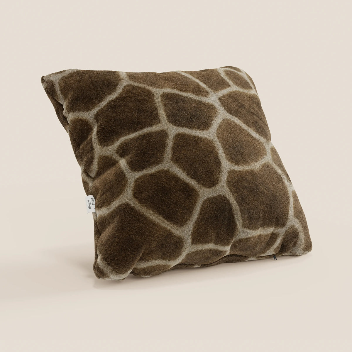 Il cuscino Wild della collezione Wild di divitt.sbs è un cuscino quadrato di 45x45 cm in microfibra impermeabile, caratterizzato da una morbida stampa di giraffe nei colori marrone e beige, con una targhetta in tessuto bianco su un lato e su uno sfondo beige chiaro.