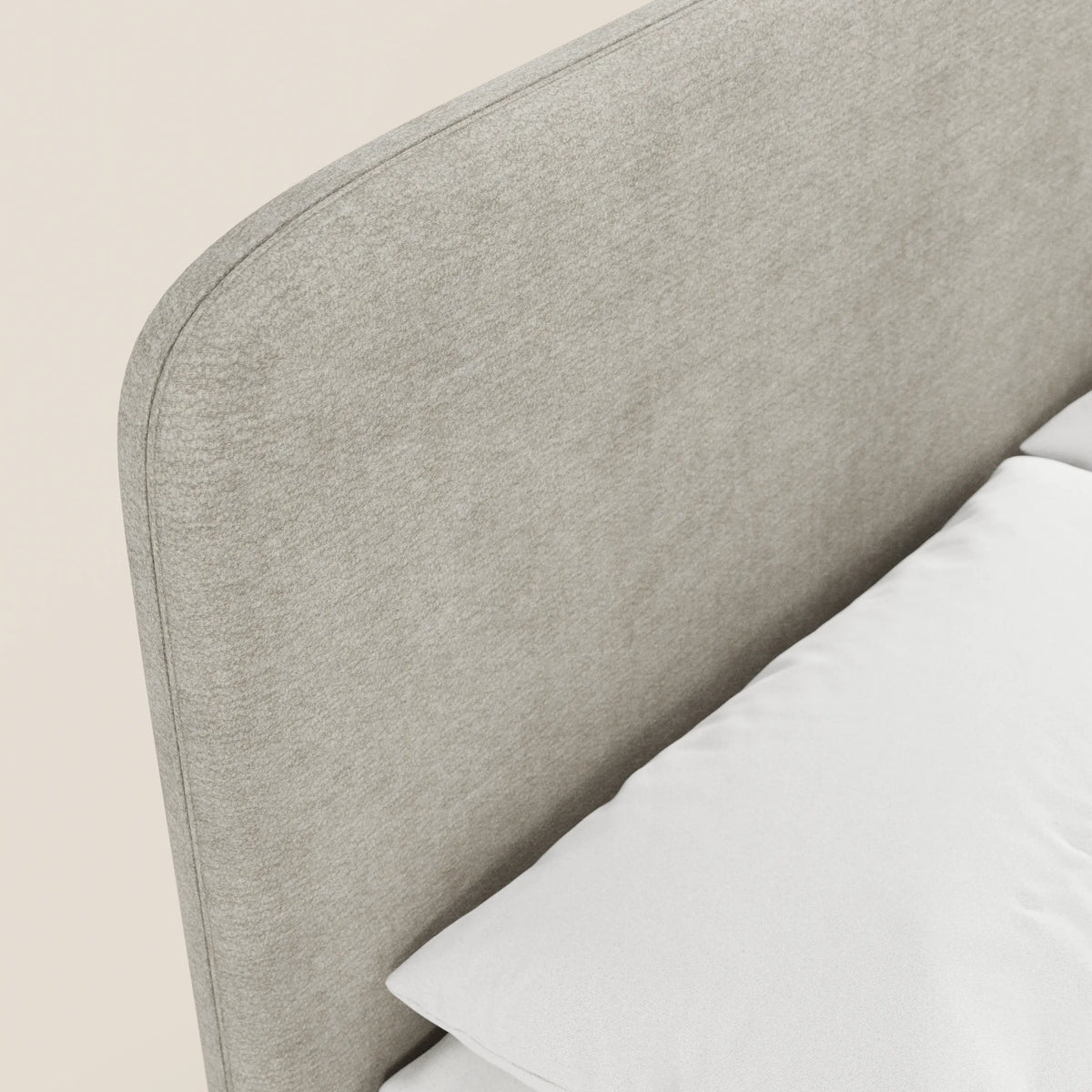 Primo piano del letto imbottito KAELOS Letto Minimal di Letti.store, caratterizzato da una testiera in tessuto ciniglia grigio chiaro con angoli arrotondati, gambe alte e vano contenitore. Presentato con biancheria da letto bianca su uno sfondo color crema per esaltarne lo stile morbido e minimalista.