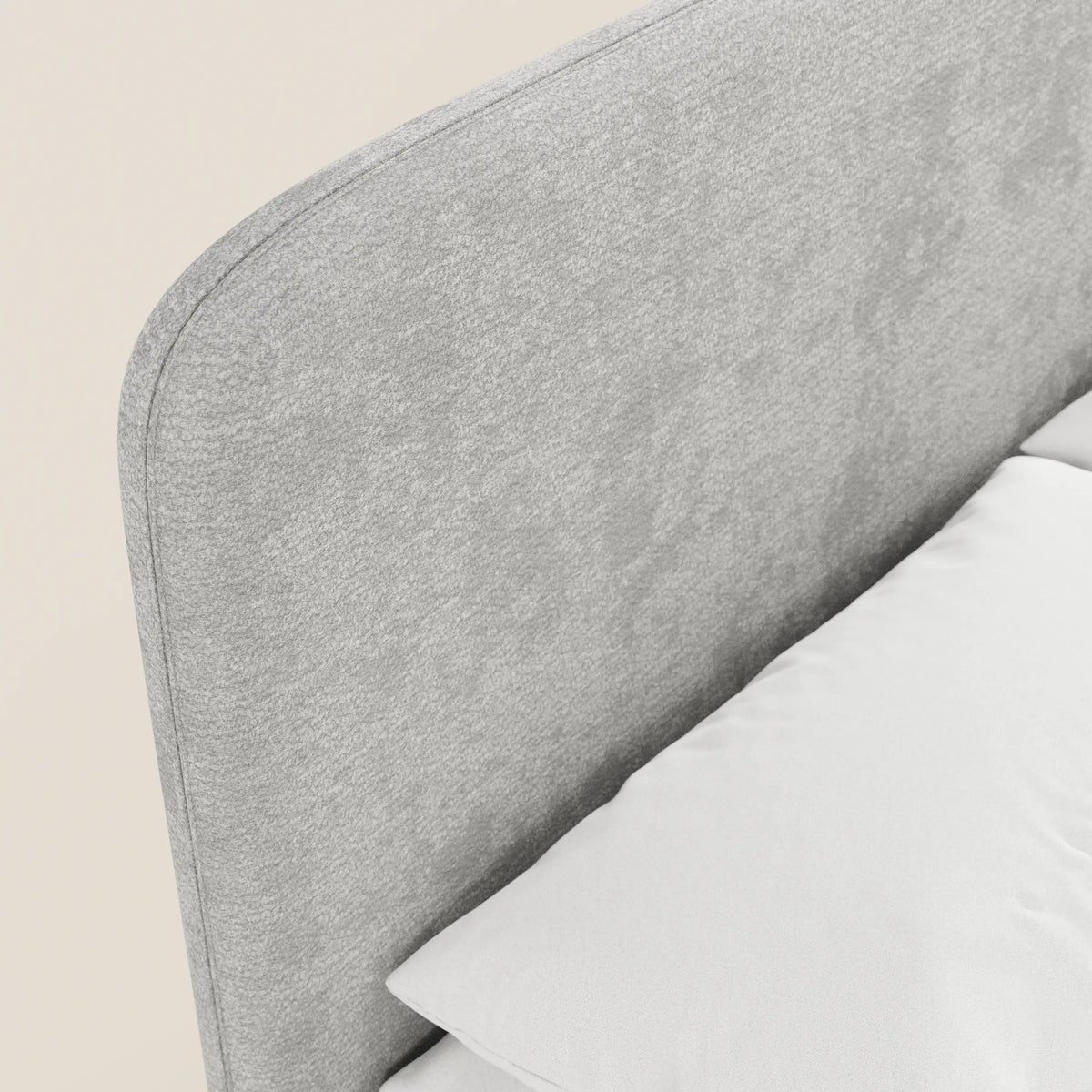 Primo piano del letto imbottito KAELOS Letto Minimal di Letti.store, caratterizzato da una testiera arrotondata in ciniglia, gambe alte e vano contenitore. Presentato in grigio chiaro con un cuscino bianco, su uno sfondo neutro della camera da letto.
