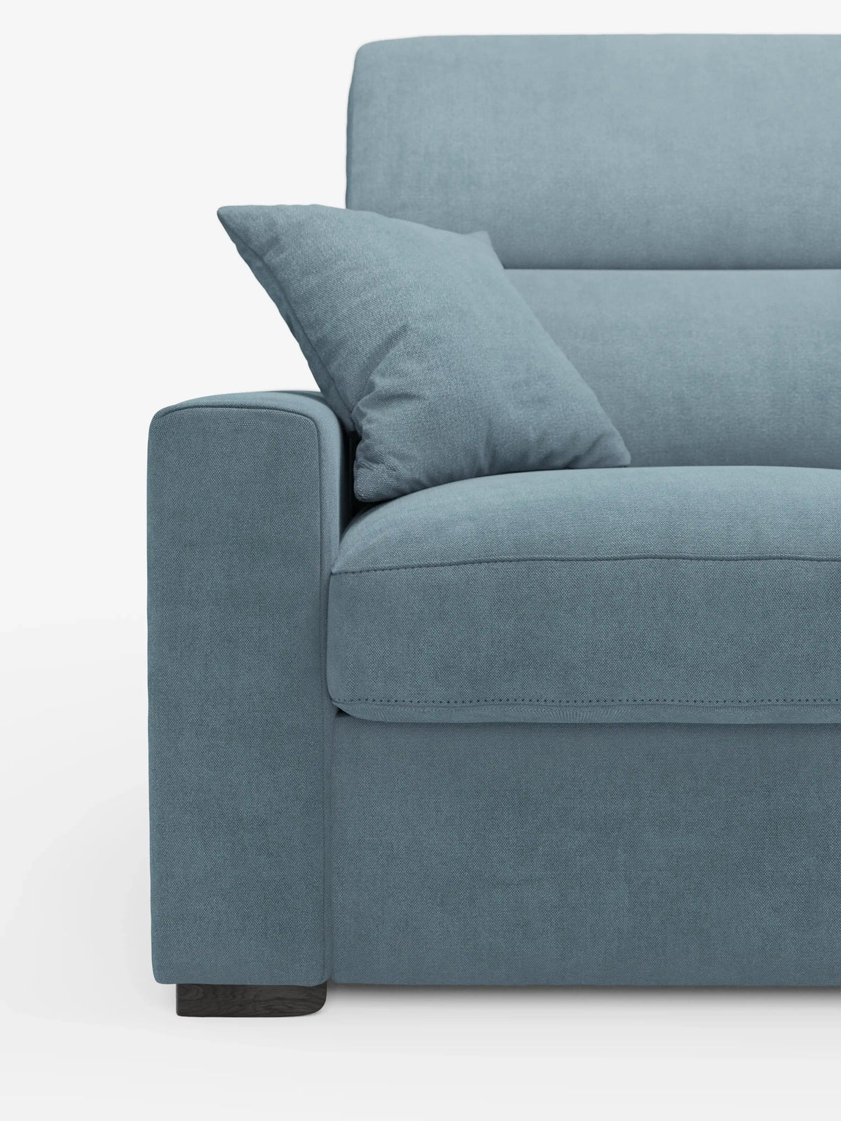 Un primo piano del moderno divano letto Maximus a 3 posti con rivestimento blu e materasso ALTO 20 cm di divitt.sbs, caratterizzato da un unico cuscino coordinato sulla seduta. L'immagine mostra il lato sinistro, mettendo in risalto il bracciolo, la seduta, lo schienale con poggiatesta reclinabili in tessuto antimacchia Oeko-Tex e la gamba corta in legno scuro. Lo sfondo è bianco a tinta unita.