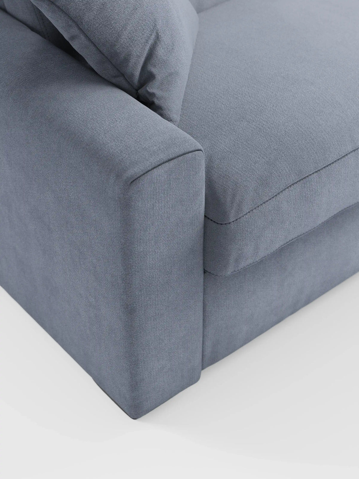 Primo piano del divano letto Maximus a 3 posti con materasso ALTO da 20 cm di divitt.sbs, rivestito in morbido tessuto smacchiabile Oeko-Tex di colore grigio medio. L’immagine mette in risalto i morbidi cuscini della seduta e dello schienale, un ampio bracciolo imbottito con poggiatesta reclinabili e linee pulite e semplici. Sullo sfondo bianco, spicca il design minimalista del divano.
