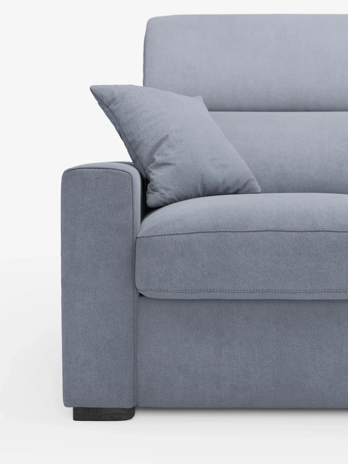 Primo piano del lato sinistro del divano letto a 3 posti Maximus con materasso ALTO da 20 cm di divitt.sbs, realizzato in tessuto azzurro resistente alle macchie certificato Oeko-Tex, con cuscino quadrato abbinato, bracciolo, cuscino di seduta e parte dello schienale con poggiatesta regolabili; il tutto su uno sfondo bianco a tinta unita.