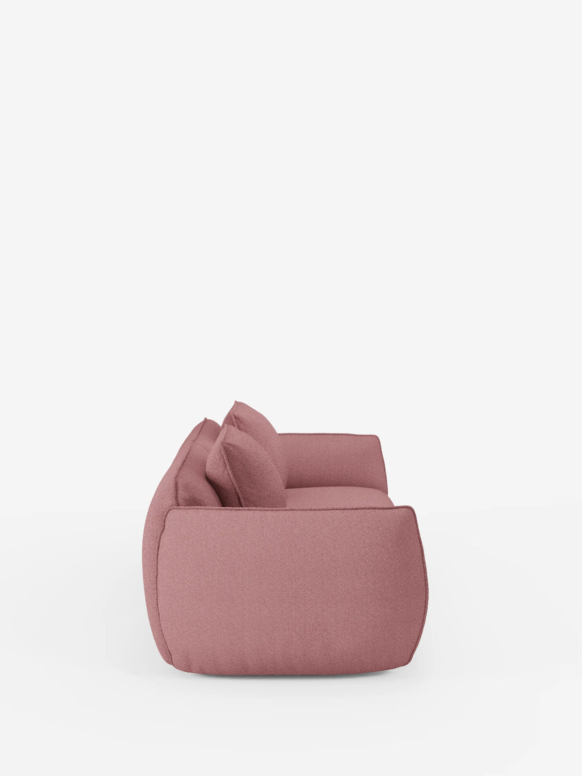 Vista laterale del divano Nimbus a 3 posti, modulare e componibile, da 250 cm di divitt.sbs, caratterizzato da un morbido rivestimento sfoderabile rosa effetto cotone e resistente alle macchie (t33), bordi arrotondati e due cuscini coordinati. Questo divano moderno ha un'altezza ridotta da terra e presenta un design minimalista e accogliente su uno sfondo bianco a tinta unita.