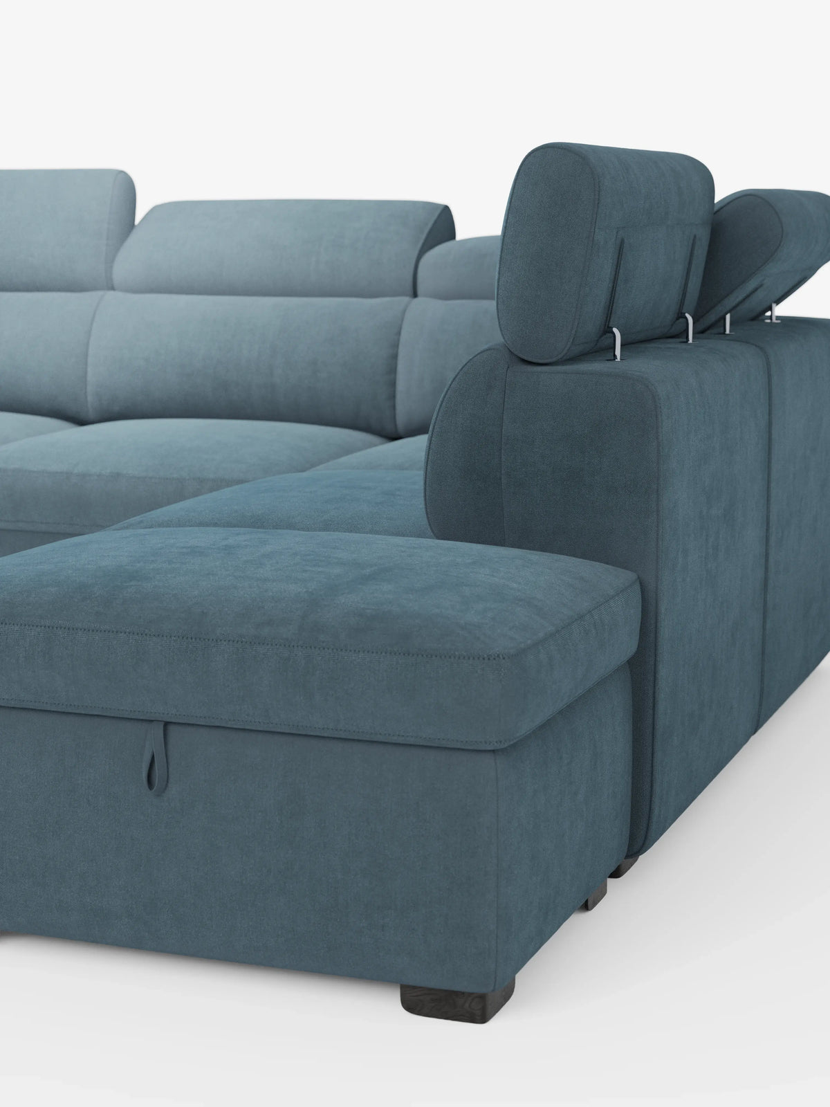 Un divano angolare reversibile Titano blu in stile contemporaneo di divitt.sbs, rivestito in morbido tessuto Oeko-Tex® antimacchia, dotato di poggiatesta regolabili e provvisto di una chaise longue con linguetta a strappo che rivela uno spazio portaoggetti nascosto nel pouf integrato. Il divano si caratterizza per le linee pulite e gli eleganti piedini neri ed è esposto su uno sfondo bianco a tinta unita.