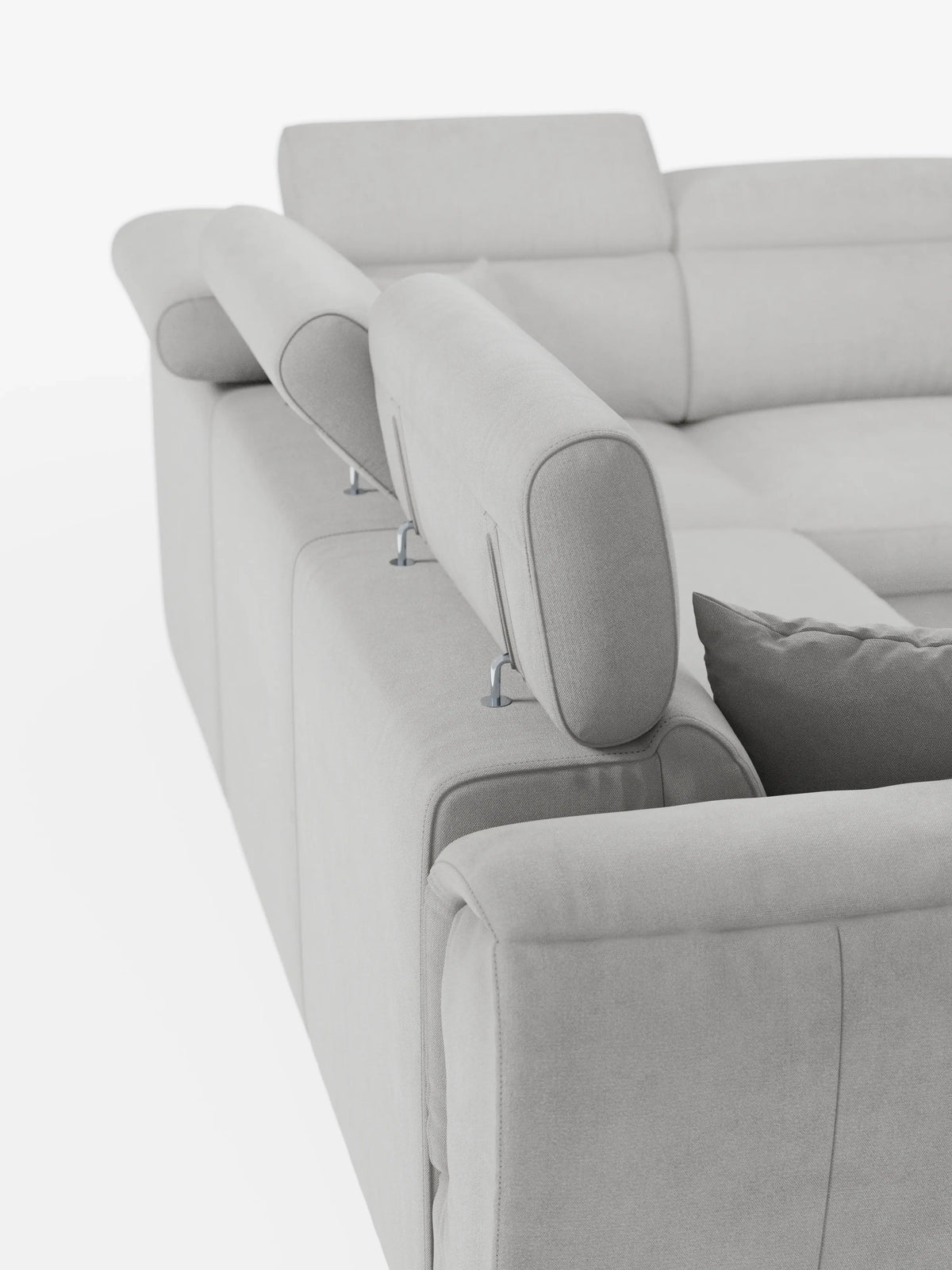 Un primo piano del divano angolare reversibile con letto estraibile e pouf contenitore "Titano" di divitt.sbs, caratterizzato da un design moderno in grigio chiaro con poggiatesta reclinabili in tessuto Smacchiabile Oeko-Tex® e un cuscino coordinato. I poggiatesta sono sollevati, lasciando intravedere eleganti meccanismi di supporto in metallo, mentre il morbido tessuto risalta sullo sfondo bianco a tinta unita.