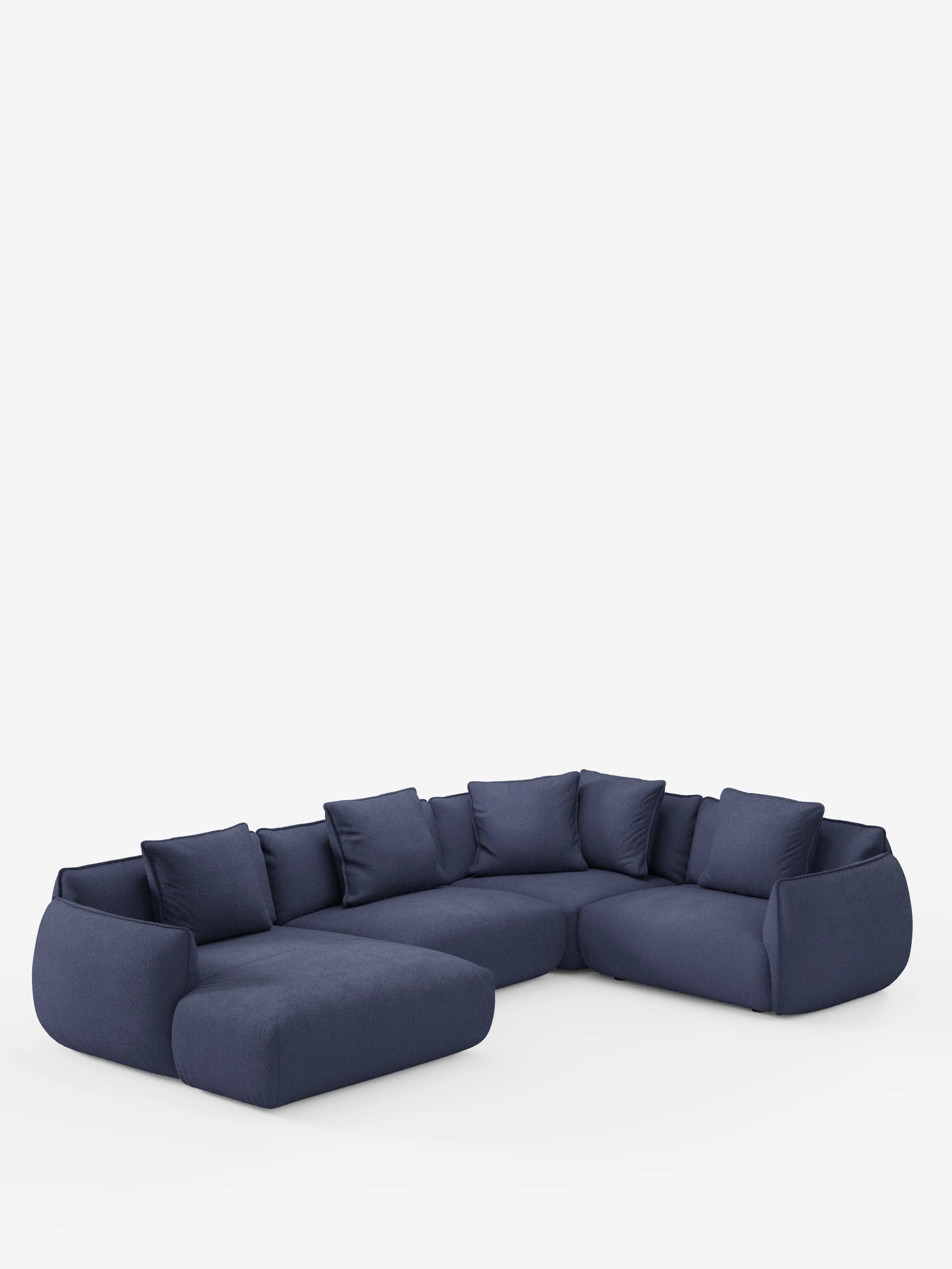 Su uno sfondo bianco a tinta unita spicca un ampio divano angolare panoramico componibile Nimbus, color blu scuro, con penisola e angolo in tessuto smacchiabile T33 di divitt.sbs. Questo divano componibile moderno e accogliente si caratterizza per i cuscini e i cuscini dello schienale morbidi e ben imbottiti, i bordi arrotondati e l’assenza di gambe a vista, incarnando alla perfezione l’eleganza dell’artigianato Made in Italy.