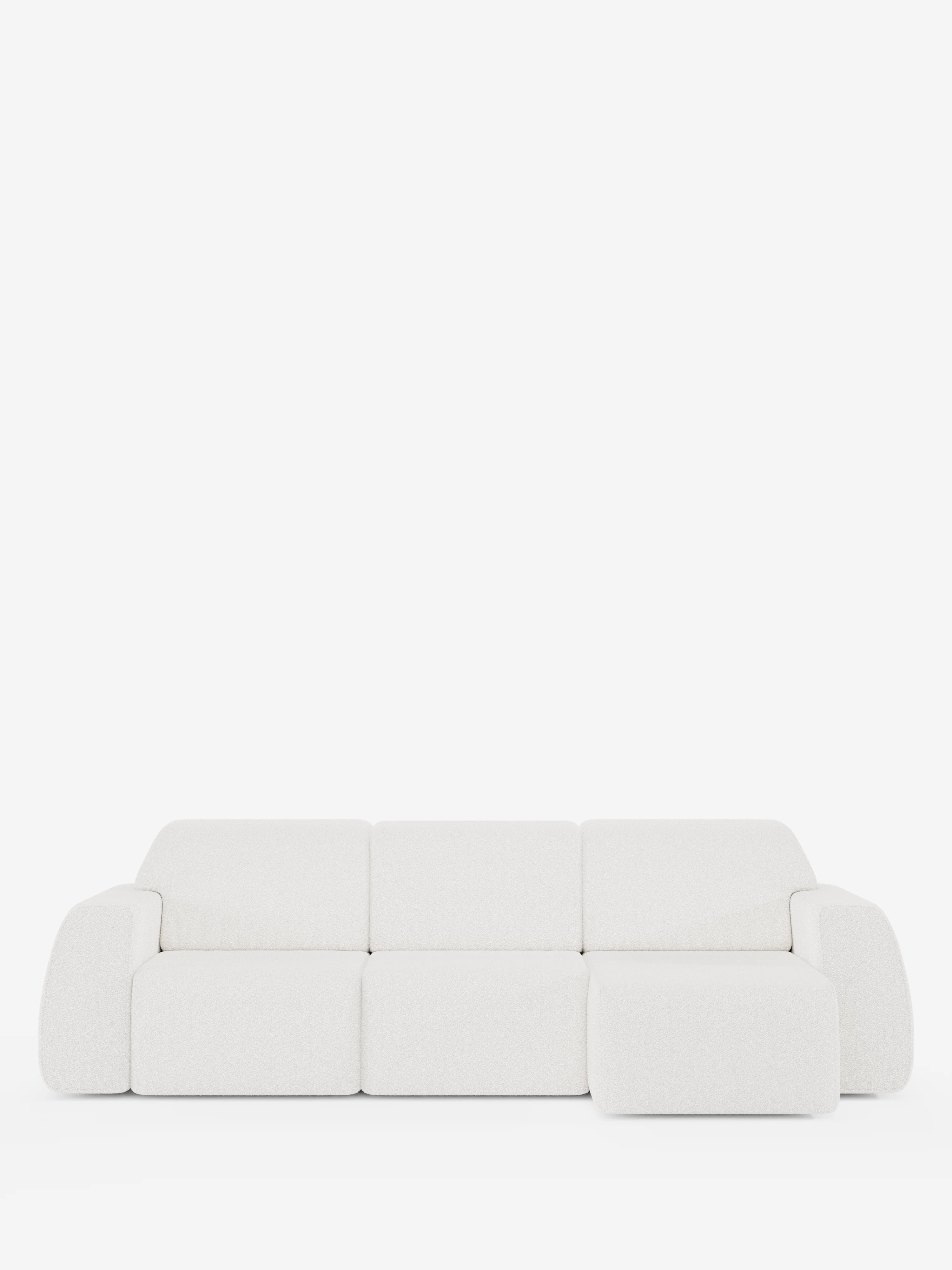 Un divano angolare Orbit contemporaneo, bianco, con penisola reversibile e tutte le sedute allungabili, rivestito in tessuto smacchiabile effetto cotone T33 di divitt.sbs, caratterizzato da un design minimalista con bordi arrotondati e una chaise longue integrata sul lato destro, è presentato su uno sfondo bianco a tinta unita. Il rivestimento antimacchia effetto cotone appare morbido e soffice.