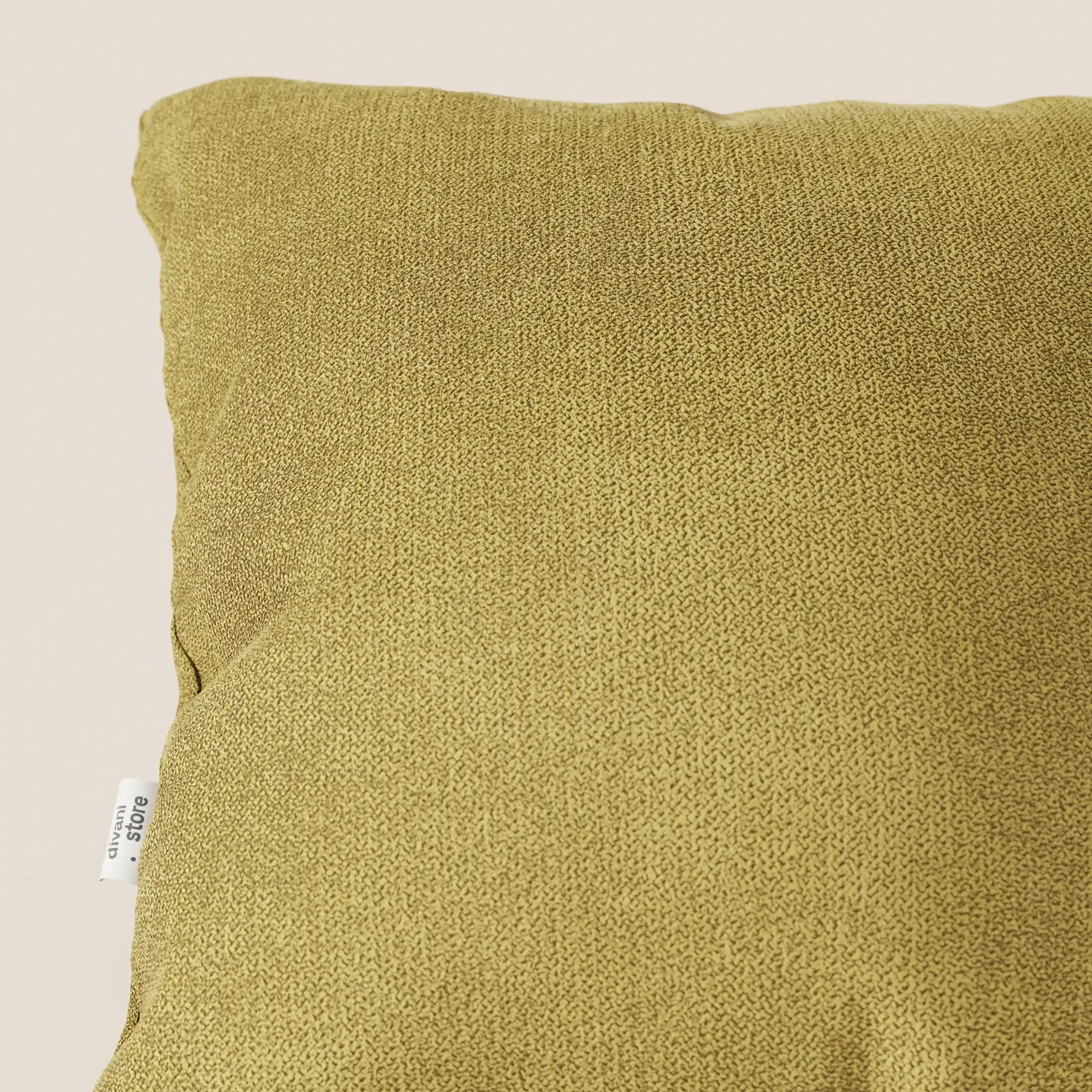 Un primo piano del cuscino Destiny 45x45 cm di divitt.sbs, in morbido tessuto impermeabile T02 giallo, mostra il suo tessuto strutturato giallo senape e la piccola etichetta laterale bianca su uno sfondo chiaro e neutro. È visibile solo la parte superiore sinistra.