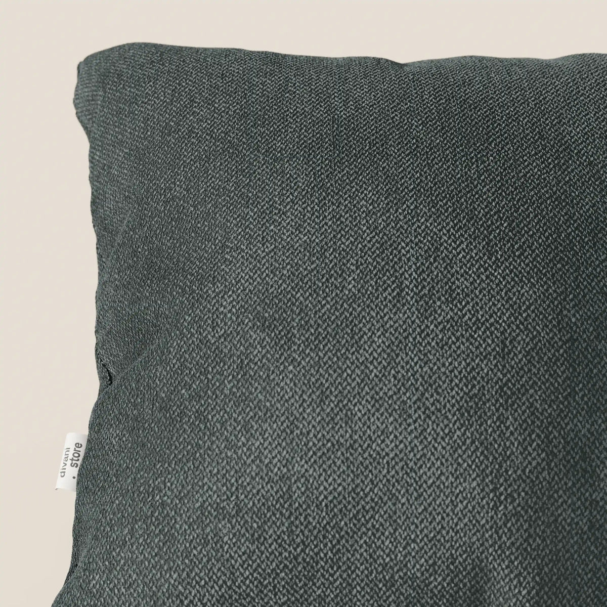 Primo piano di un cuscino Sogno di divitt.sbs in morbido tessuto verde T05 antimacchia. L'elegante trama e la piccola etichetta bianca sono visibili, mentre il cuscino occupa la maggior parte dell'immagine su uno sfondo chiaro.