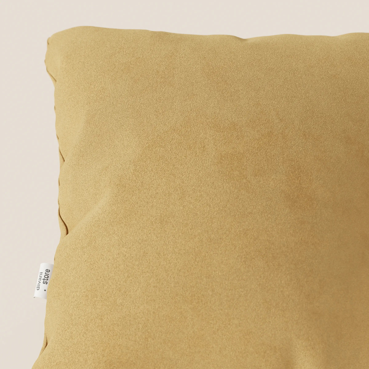 Primo piano del cuscino Jazz di divitt.sbs in T11 giallo, realizzato in microfibra tecnica antimacchia, su sfondo beige chiaro con una piccola etichetta bianca visibile sul bordo sinistro.