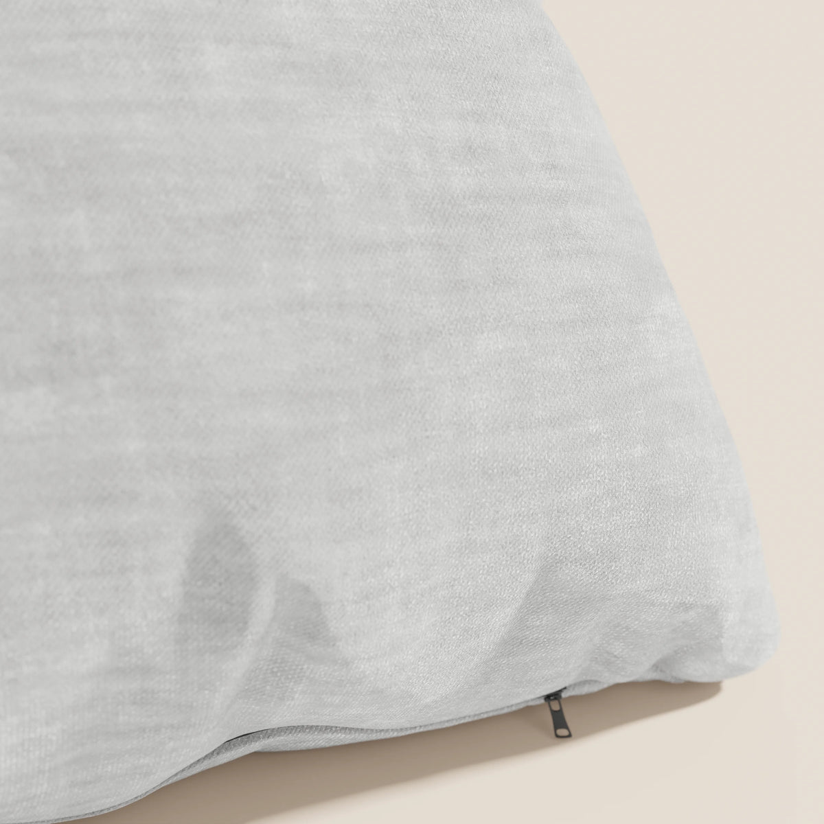 Un primo piano di Sofia, il cuscino divitt.sbs in morbido velluto nuvolato grigio chiaro, smacchiabile e impermeabile Easy Clean T35, con federa testurizzata e zip nera removibile, su superficie beige. Sfondo semplice e ordinato.