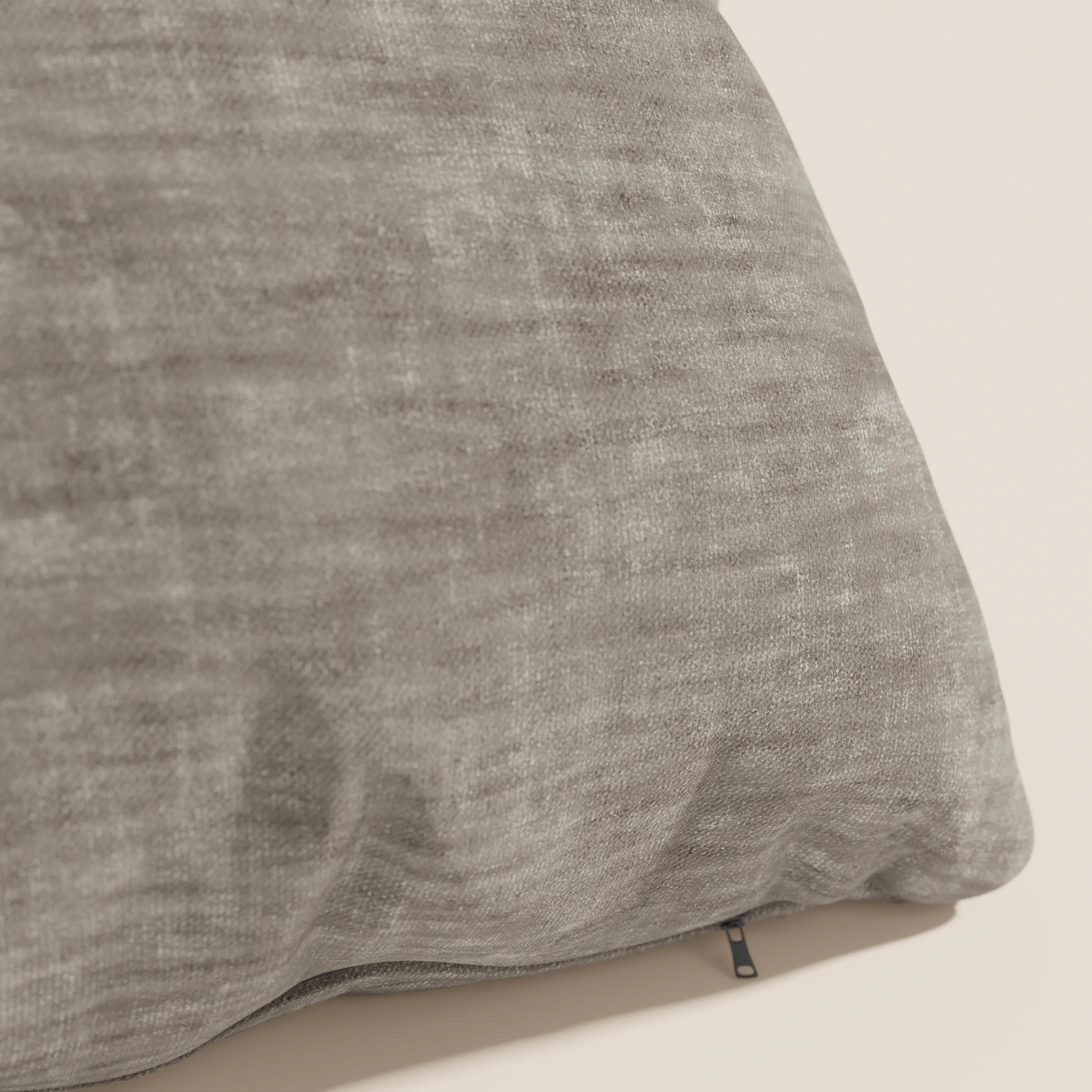 Primo piano del cuscino Sofia di divitt.sbs, in grigio. Realizzato in morbido velluto nuvolato (Easy Clean T35), è resistente alle macchie e impermeabile e presenta una cerniera nera. Lo sfondo è semplice e di colore chiaro.