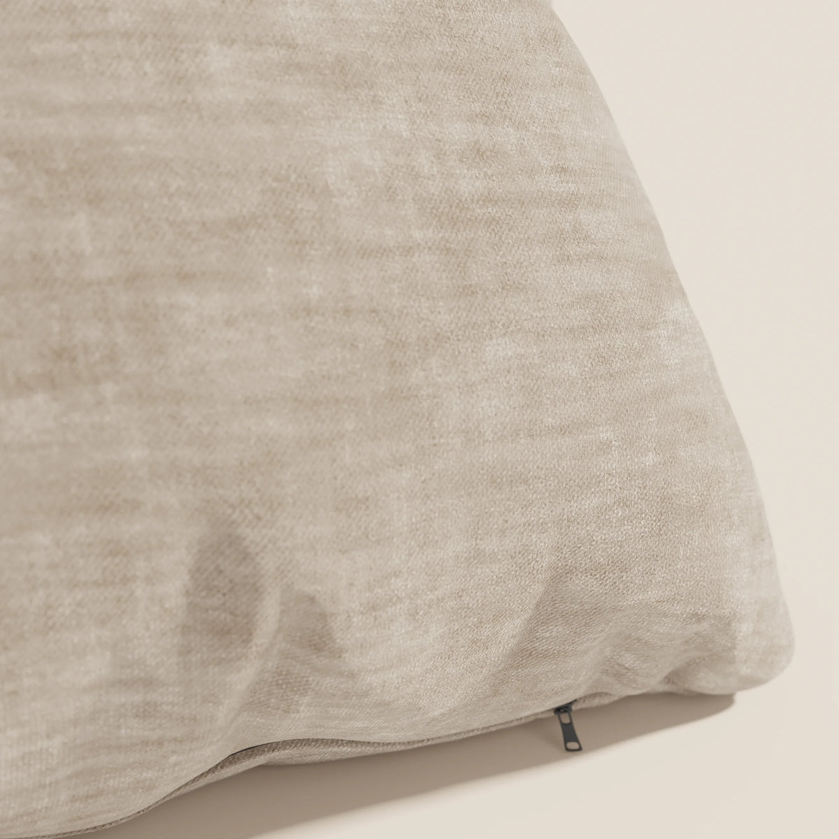 Primo piano del cuscino Sofia di divitt.sbs in beige, realizzato in morbido velluto screziato Easy Clean T35, antimacchia e impermeabile. Una piccola cerniera nera è visibile su una cucitura e conferisce un aspetto accogliente e neutro.