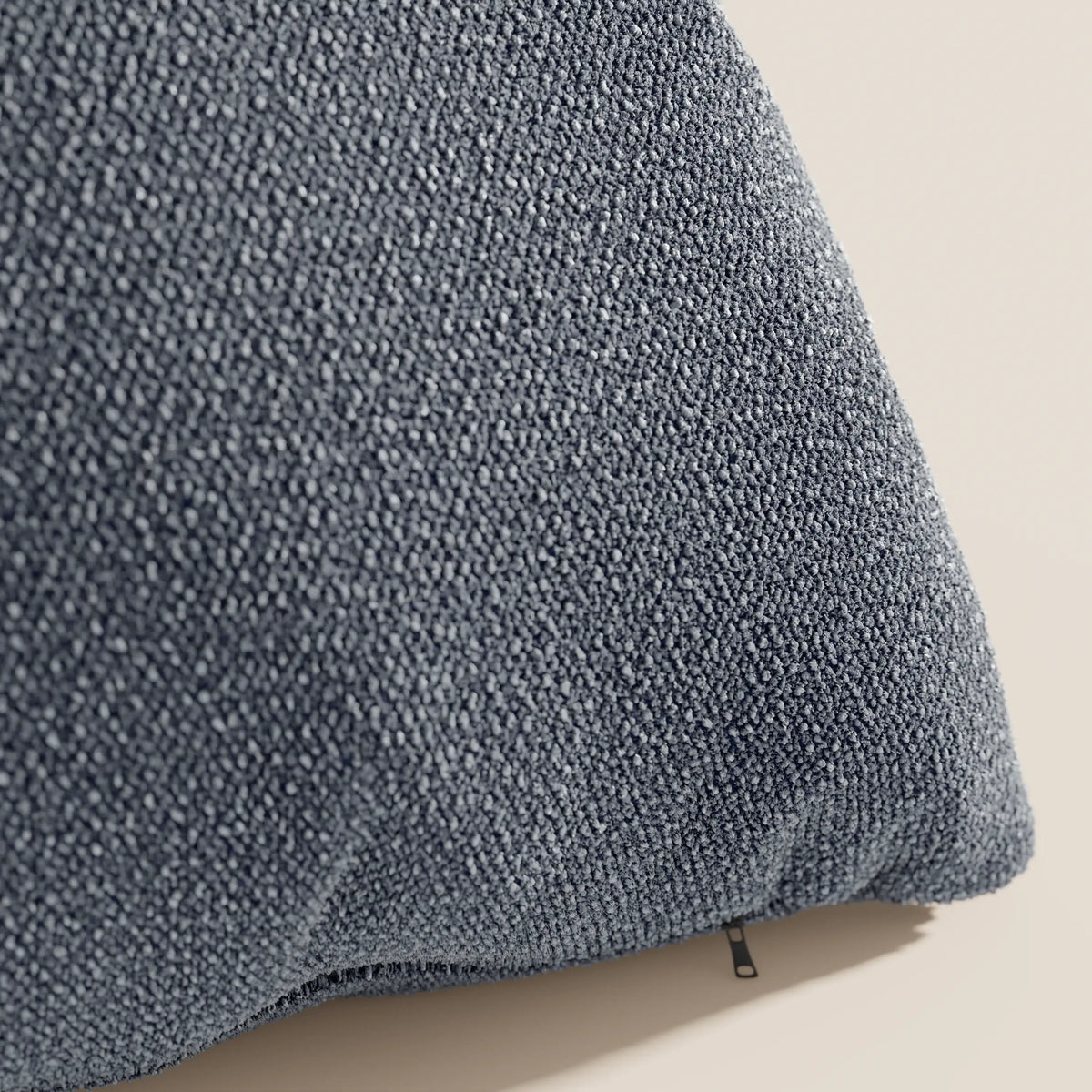 Primo piano del cuscino Lambada di divitt.sbs in blu scuro, caratterizzato da una trama a boucle con piccoli passanti e una sottile cerniera nera. Realizzato in tessuto naturale simil-cotone impermeabile e antimacchia.