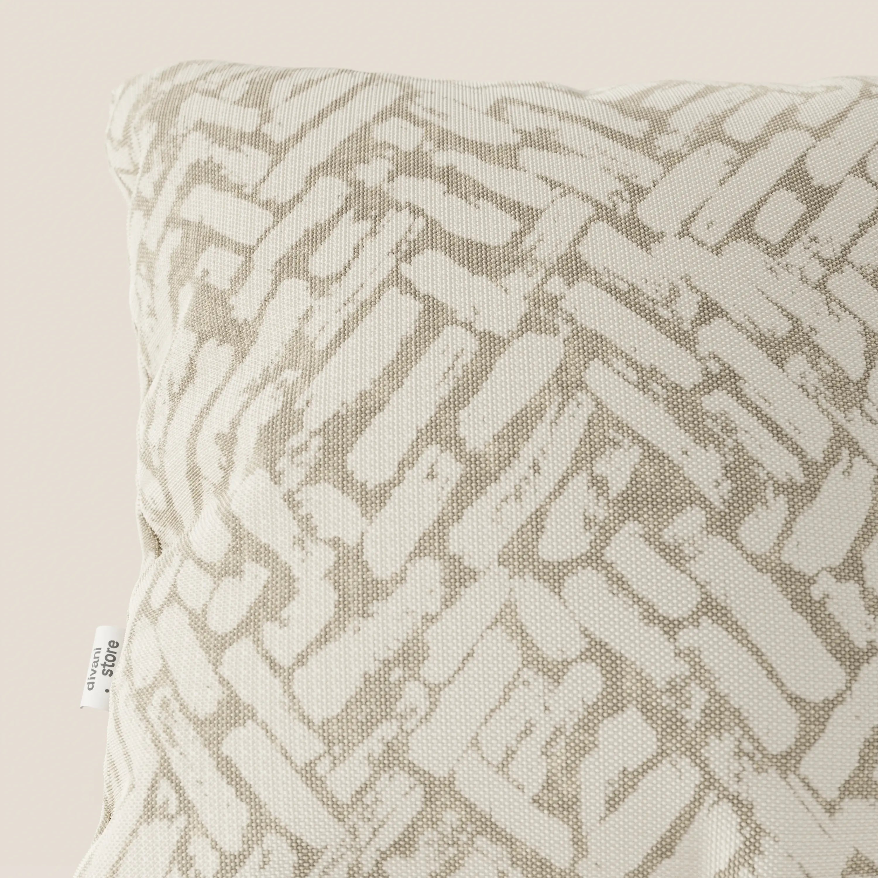 Primo piano del cuscino geometrico Brick di divitt.sbs, presentato in tessuto idrorepellente beige con un motivo ispirato ai mattoni e una piccola etichetta bianca. Il suo design moderno spicca su uno sfondo semplice e chiaro.
