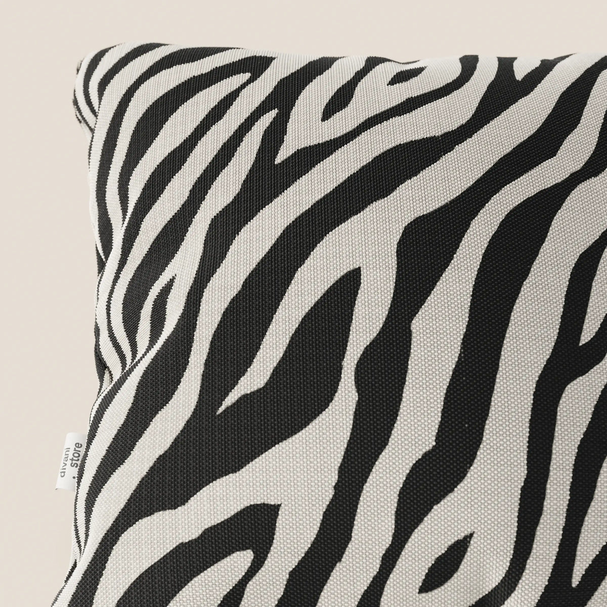 Primo piano di divitt.sbs Stripe cuscini geometrici in tessuto Idrorepellente, nero, con motivo zebrato bianco e nero su sfondo beige chiaro. Sul bordo sinistro è visibile una piccola etichetta in tessuto bianco.