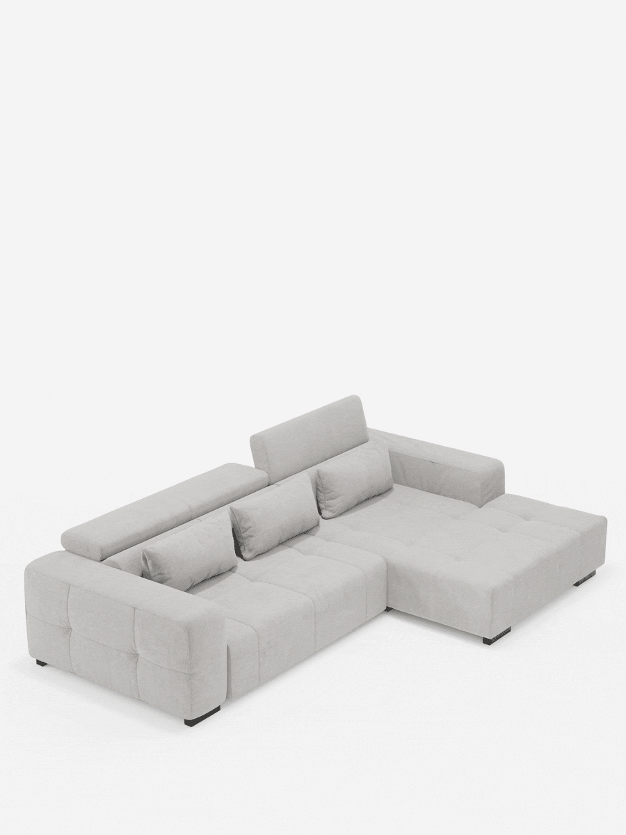 Il divano angolare Monarch con penisola e funzione Relax Elettrico per l’allungamento delle sedute di divitt.sbs è un divano componibile a forma di L di colore grigio chiaro, rivestito in morbido tessuto T31 resistente alle macchie, con cuscini trapuntati, braccioli squadrati e poggiatesta reclinabili regolabili. Corredato da due cuscini decorativi abbinati e messo in risalto da uno sfondo bianco a tinta unita, questo divano esalta il suo design contemporaneo e minimalista.