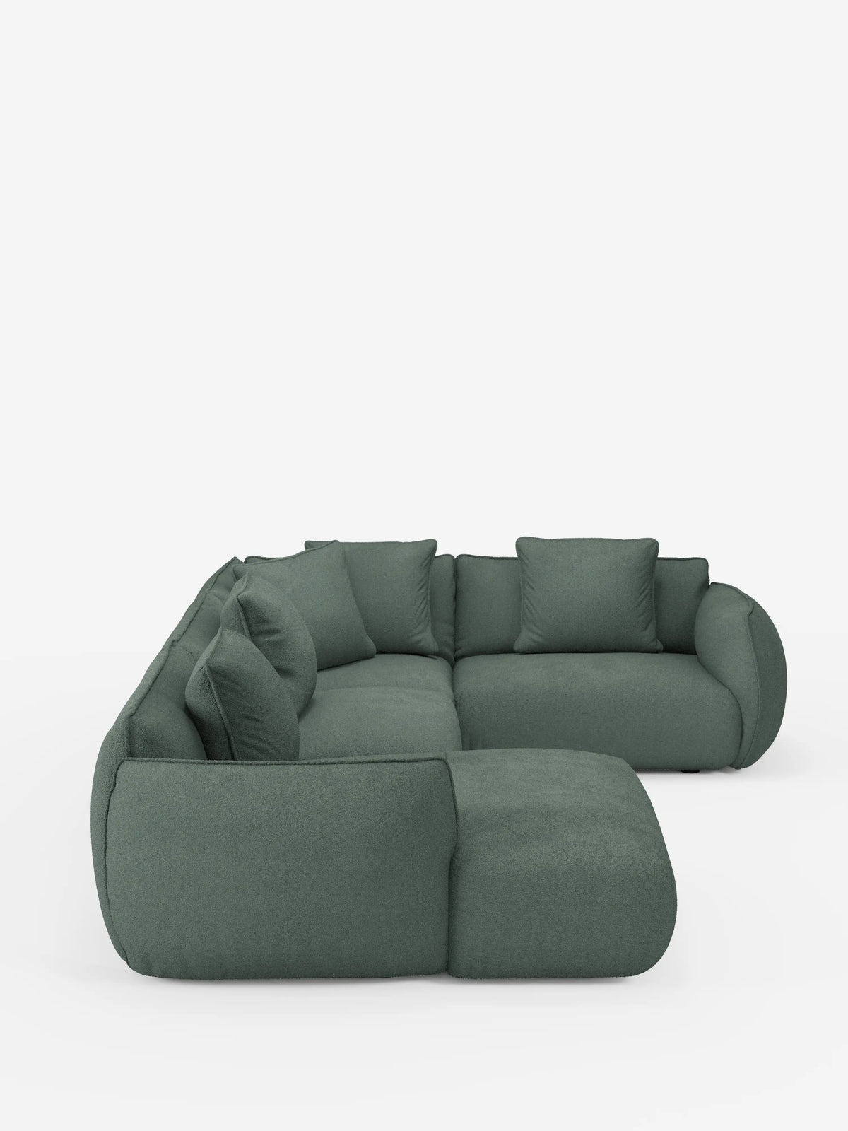 Un divano angolare panoramico componibile Nimbus in stile contemporaneo con penisola e angolo, rivestito in tessuto antimacchia T33 di divitt.sbs, caratterizzato da un design modulare a forma di L con bordi arrotondati e morbidi cuscini, rivestito in tessuto verde tenue antimacchia, ripreso da una prospettiva laterale obliqua su uno sfondo bianco.