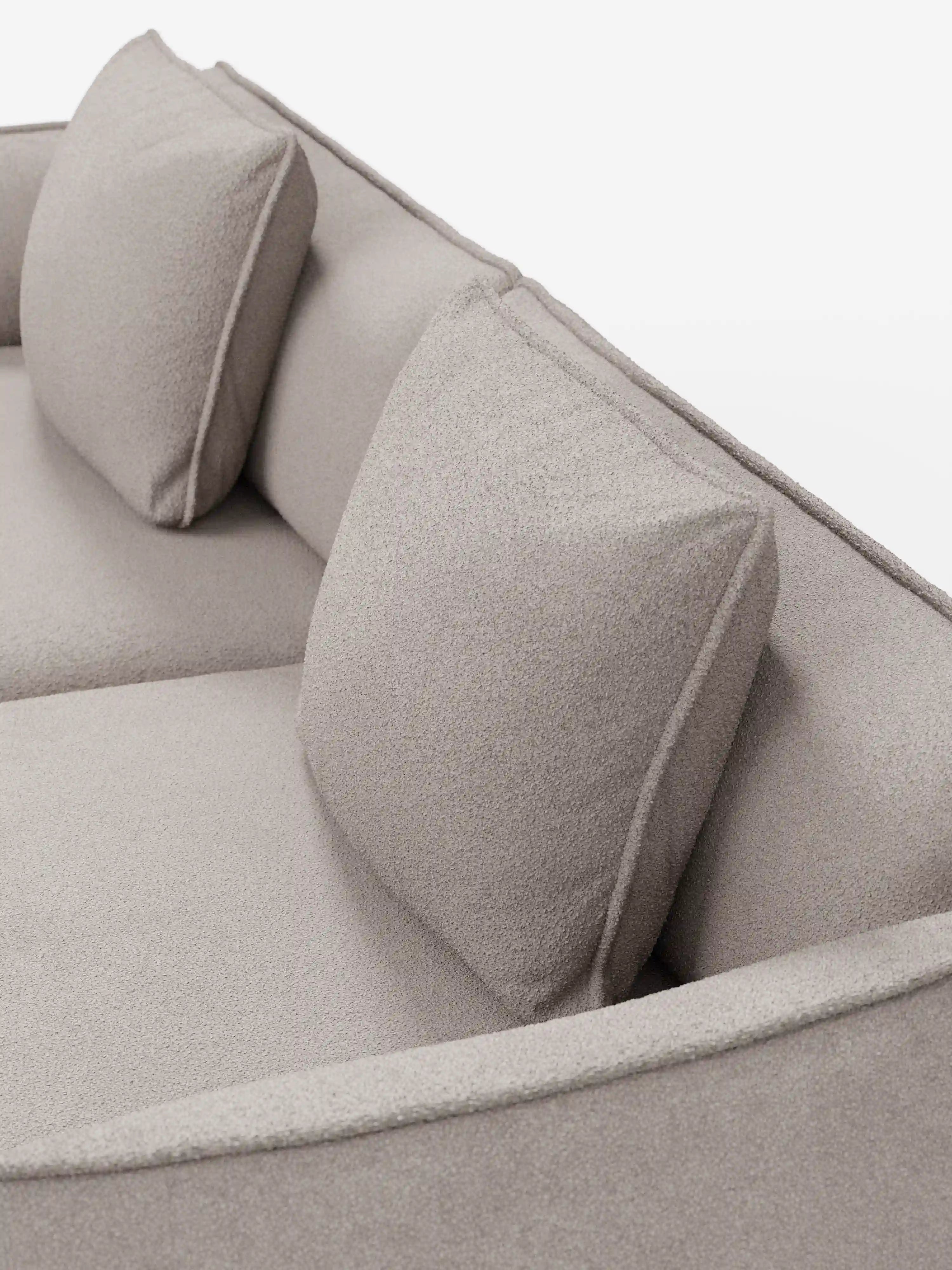 Primo piano del divano modulare e componibile Nimbus a 3 posti di divitt.sbs, qui presentato in un moderno tessuto t33 beige effetto cotone, resistente alle macchie. Caratterizzato da due cuscini schienali quadrati, questo divano da 250 cm si distingue per il rivestimento testurizzato, le linee pulite e il design minimalista su uno sfondo bianco a tinta unita.