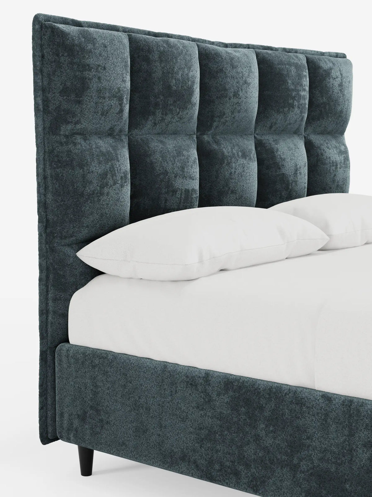 Un primo piano di un letto imbottito AURO color verde acqua scuro con contenitore e testiera alta capitonné in ciniglia Oeko-Tex®, caratterizzata da un motivo a quadrati e da una trama fitta, rivestito con lenzuola bianchissime su uno sfondo chiaro e uniforme.