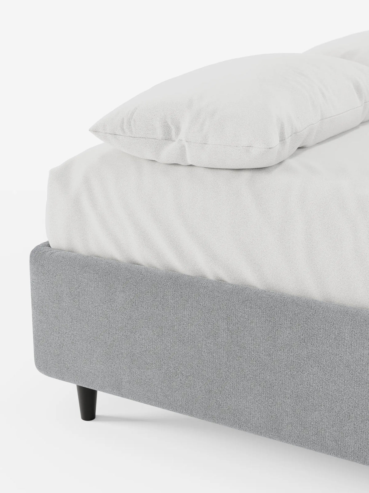 Un letto sommier imbottito ERON con contenitore, rivestito in tessuto impermeabile certificato Oeko-Tex color grigio chiaro, caratterizzato da un design minimalista su gambe corte scure, con lenzuola bianche immacolate su uno sfondo bianco a tinta unita.