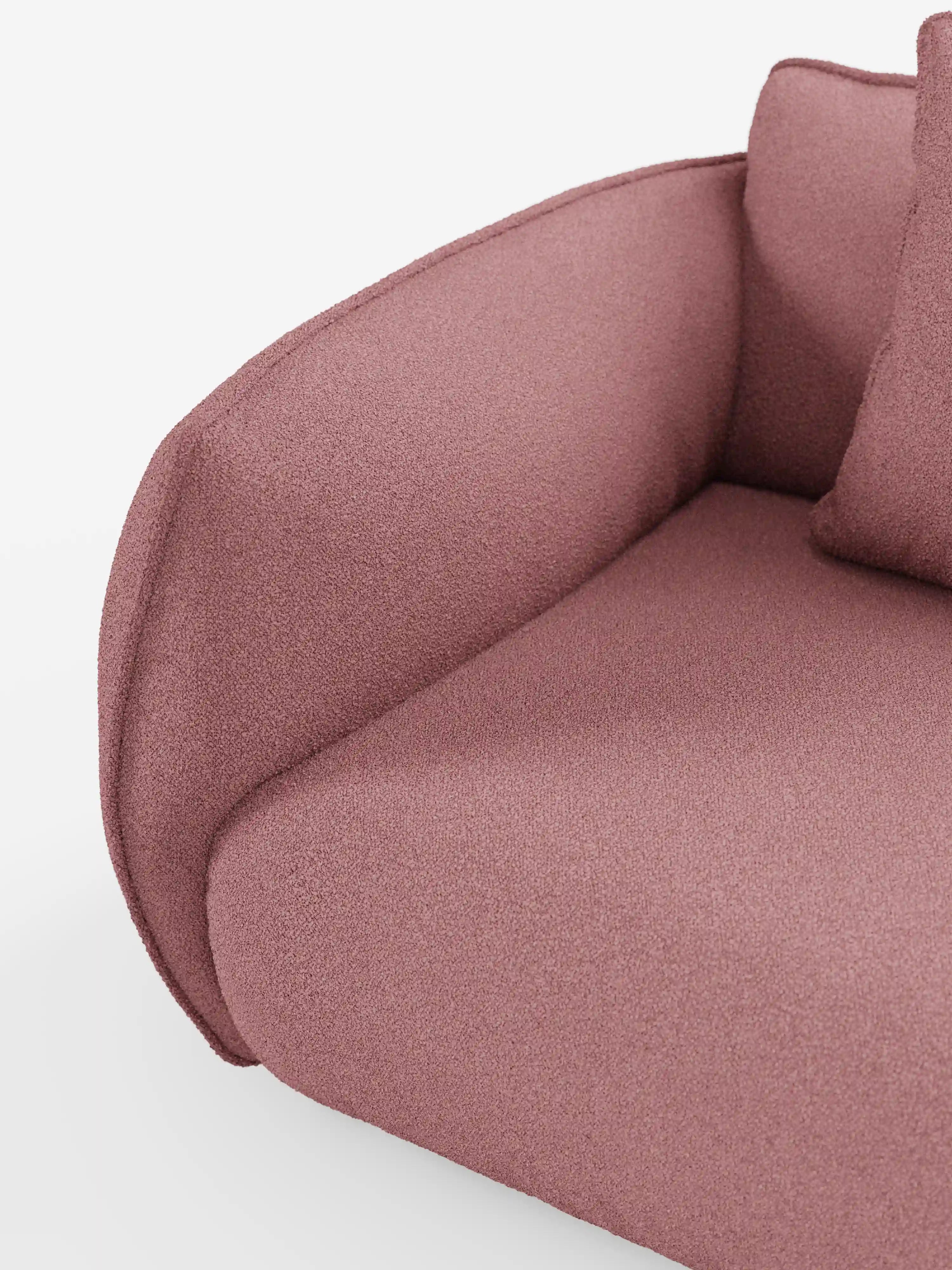 Un primo piano del divano modulare a 3 posti Nimbus di divitt.sbs, realizzato in morbido tessuto smacchiabile effetto cotone T33, caratterizzato da un rivestimento rosa testurizzato con braccioli arrotondati e cuscini di seduta. L’immagine mostra una parte dello schienale e un cuscino decorativo abbinato su uno sfondo bianco. Il tessuto morbido e soffice ne esalta la versatilità e il comfort, caratteristiche tipiche dei divani componibili di alta qualità.