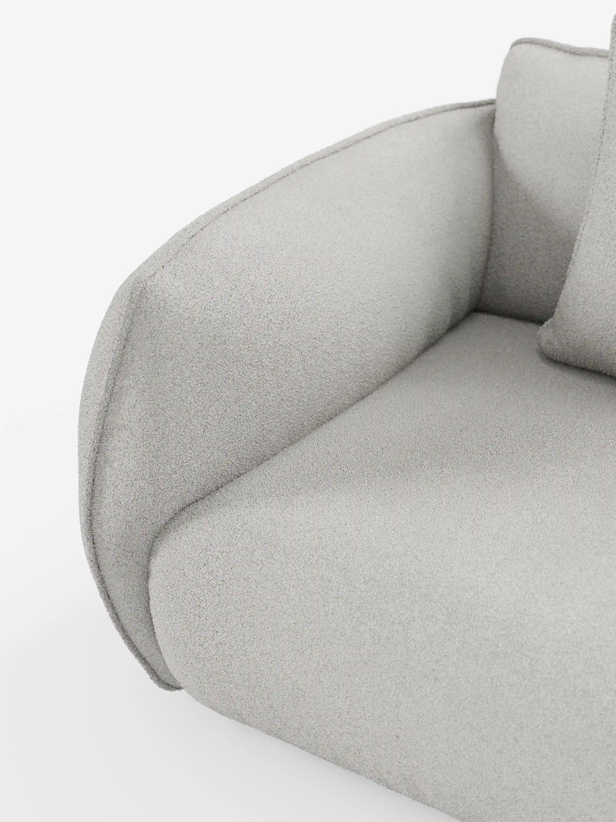 Primo piano del divano Nimbus a 3 posti, modulare e componibile, da 250 cm di divitt.sbs, rivestito in tessuto smacchiabile effetto cotone T33 color grigio chiaro. L'immagine mette in risalto il bracciolo dalle curve eleganti, il cuscino di seduta e parte dello schienale, evidenziando il tessuto morbido, soffice e sfoderabile con finitura testurizzata. Le linee fluide sottolineano il design contemporaneo di questo divano versatile su uno sfondo bianco.
