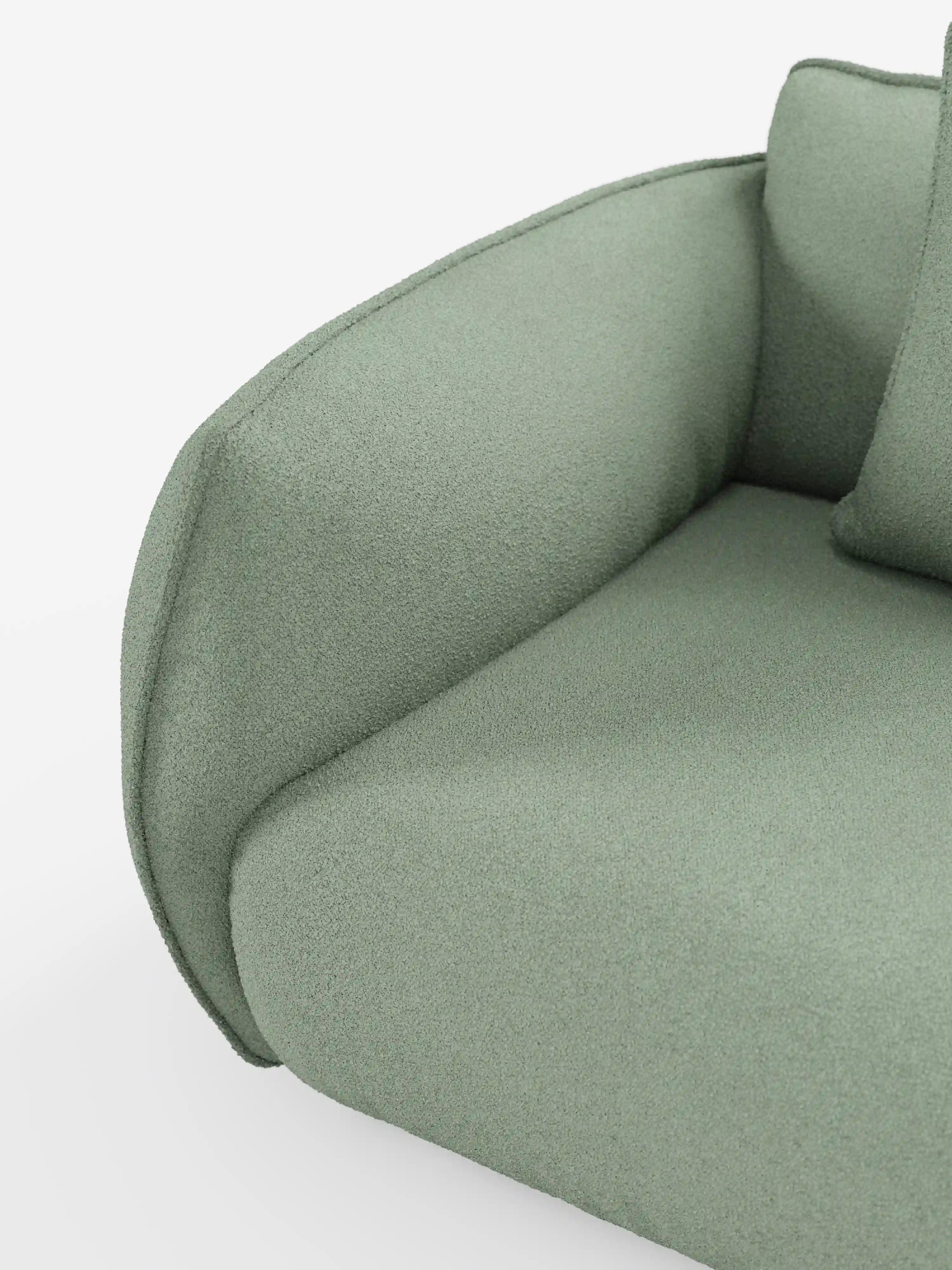 Primo piano del divano Nimbus a 3 posti, modulare e componibile, di divitt.sbs, in un moderno verde salvia, rivestito in morbido tessuto effetto cotone antimacchia (tessuto smacchiabile effetto cotone t33). L'immagine mette in risalto il bracciolo ricurvo, il cuscino di seduta e parte di un cuscino su uno sfondo bianco, esaltandone il design lussuoso ma minimalista.