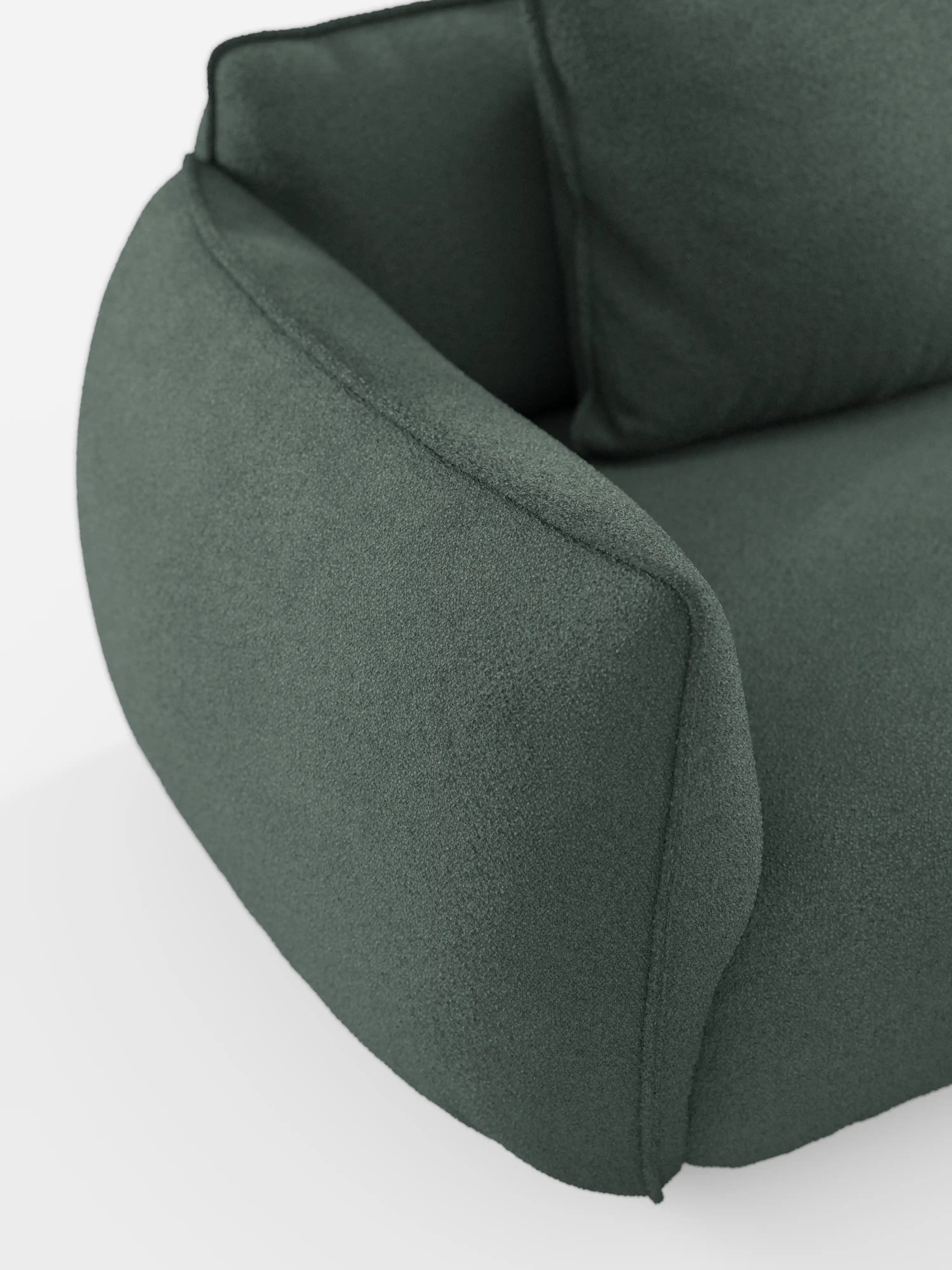 Primo piano del bracciolo e della seduta del divano angolare con penisola componibile Nimbus di divitt.sbs, rivestito in tessuto T33 effetto cotone verde scuro, resistente alle macchie. Questo divano moderno presenta un design morbido e imbottito, con bordi arrotondati e uno stile contemporaneo minimalista, valorizzato dai dettagli delle cuciture a vista. In primo piano su uno sfondo bianco a tinta unita.