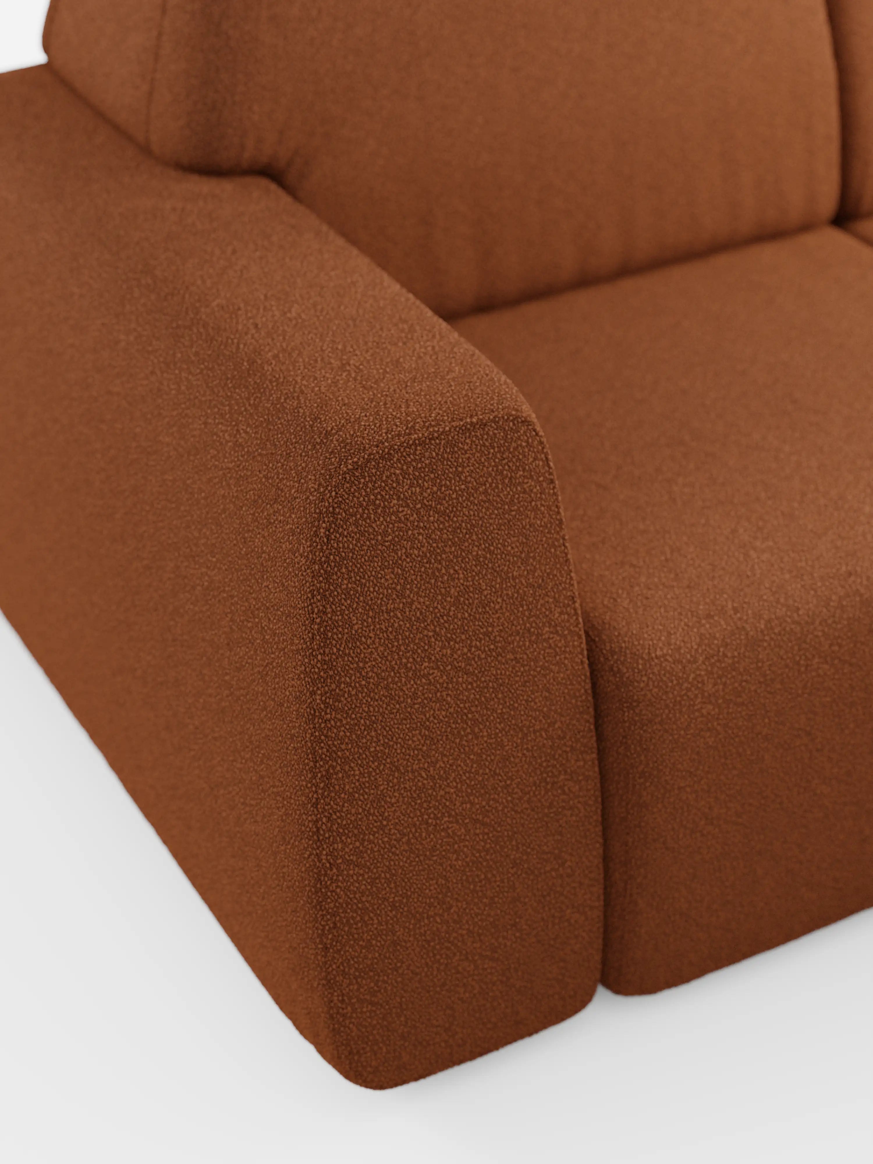 Primo piano del divano Orbit con 3 sedute scorrevoli e allungabili in tessuto effetto cotone smacchiabile T33 di divitt.sbs, che mette in risalto il suo design contemporaneo con il rivestimento testurizzato color ruggine. L’immagine mette in risalto l’ampio bracciolo rettangolare, il cuscino di seduta e una porzione dello schienale per evidenziare il tessuto a effetto cotone granuloso. Questo modello è dotato di rivestimenti completamente sfoderabili per una facile manutenzione. Lo sfondo bianco crea un