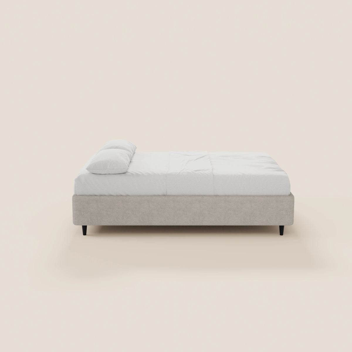 Il letto sommier ERON di Letti.store presenta una base in tessuto impermeabile Oeko-Tex grigio chiaro, lenzuola bianche, un cuscino bianco, gambe corte di colore scuro e un design pulito e moderno — qui raffigurato di profilo su uno sfondo beige chiaro.