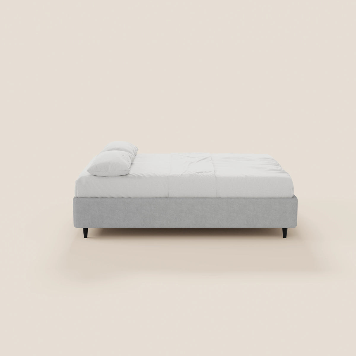 Il letto sommier ERON di Letti.store presenta un design moderno e minimalista, con una struttura imbottita impermeabile Oeko-Tex di colore grigio chiaro, gambe nere, materasso e biancheria da letto bianchi, ed è raffigurato di profilo su uno sfondo bianco sporco.