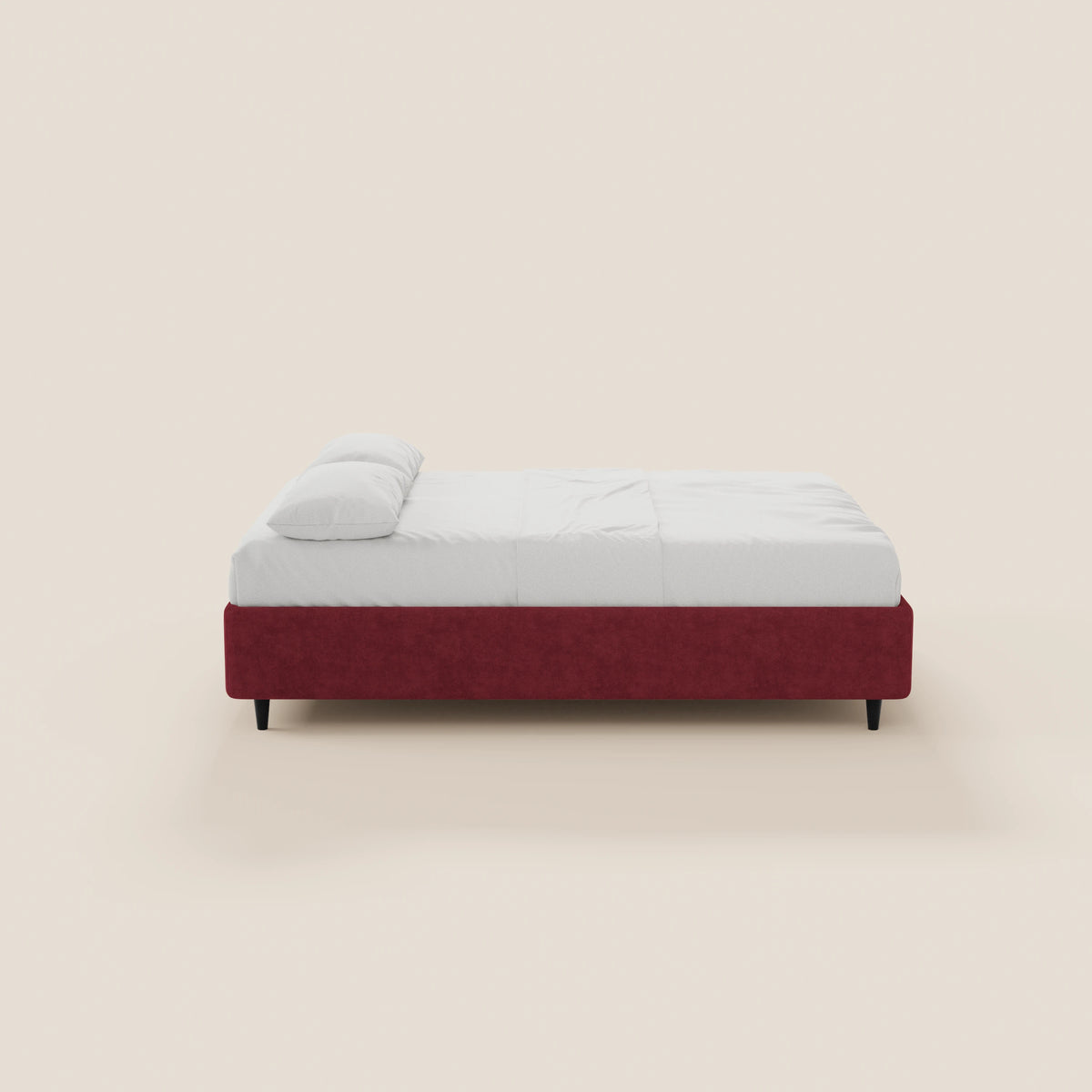 Il letto sommier imbottito ERON di Letti.store presenta una struttura bassa in tessuto impermeabile Oeko-Tex di colore rosso intenso con gambe nere. È rifinito con cura con lenzuola bianche e un unico cuscino, su uno sfondo beige chiaro, visto di profilo.