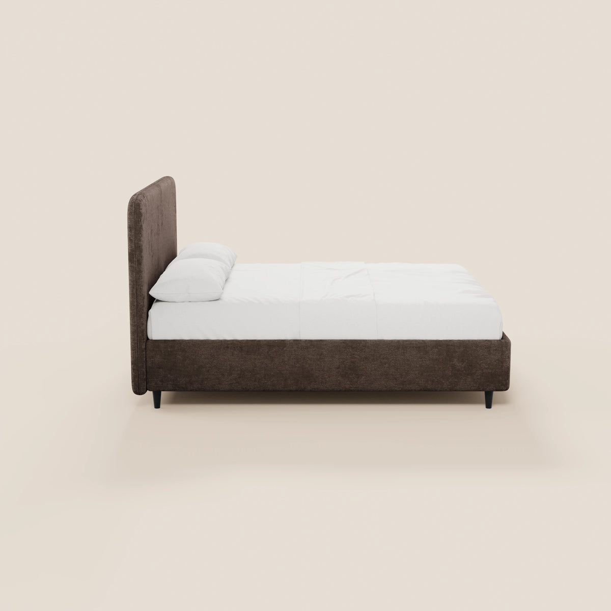 Il letto KAELOS minimal imbottito di Letti.store presenta una testiera alta e arrotondata in tessuto chenille, gambe alte di colore scuro, una base contenitore, biancheria da letto bianca e due cuscini. Immagine laterale su sfondo beige chiaro, dal design elegante e minimalista.