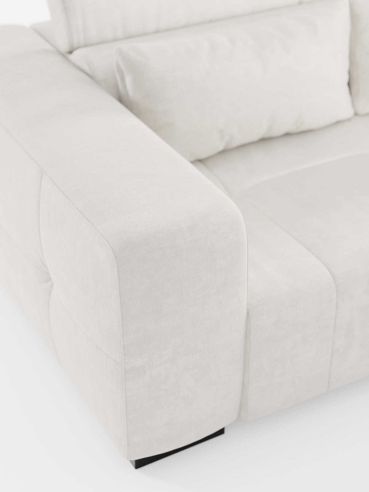 Primo piano del divano Monarch con funzione relax elettrica per l’allungamento delle sedute e poggiatesta reclinabile, realizzato in morbido tessuto lavabile T31 di divitt.sbs. L’immagine mette in risalto i braccioli, la seduta e lo schienale spessi e imbottiti, esaltando il tessuto morbido e liscio e i delicati dettagli delle cuciture. Questo elegante divano dal design contemporaneo poggia su gambe basse nere su uno sfondo bianco.