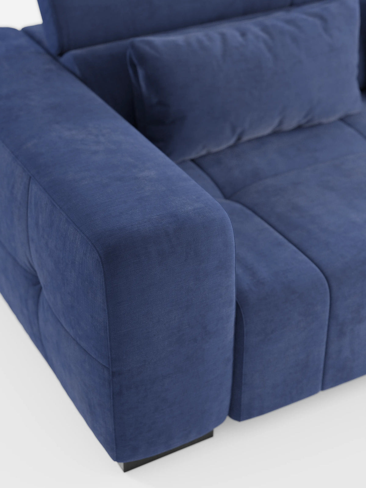 Primo piano del divano angolare con penisola e funzione relax elettrica “Monarch” di divitt.sbs, rivestito in morbido tessuto T31 resistente alle macchie, caratterizzato da braccioli e cuscini di seduta spessi e soffici. Il divano è dotato di cuscini dello schienale coordinati con poggiatesta reclinabili per un comfort ancora maggiore. Poggia su gambe corte nere su uno sfondo bianco.