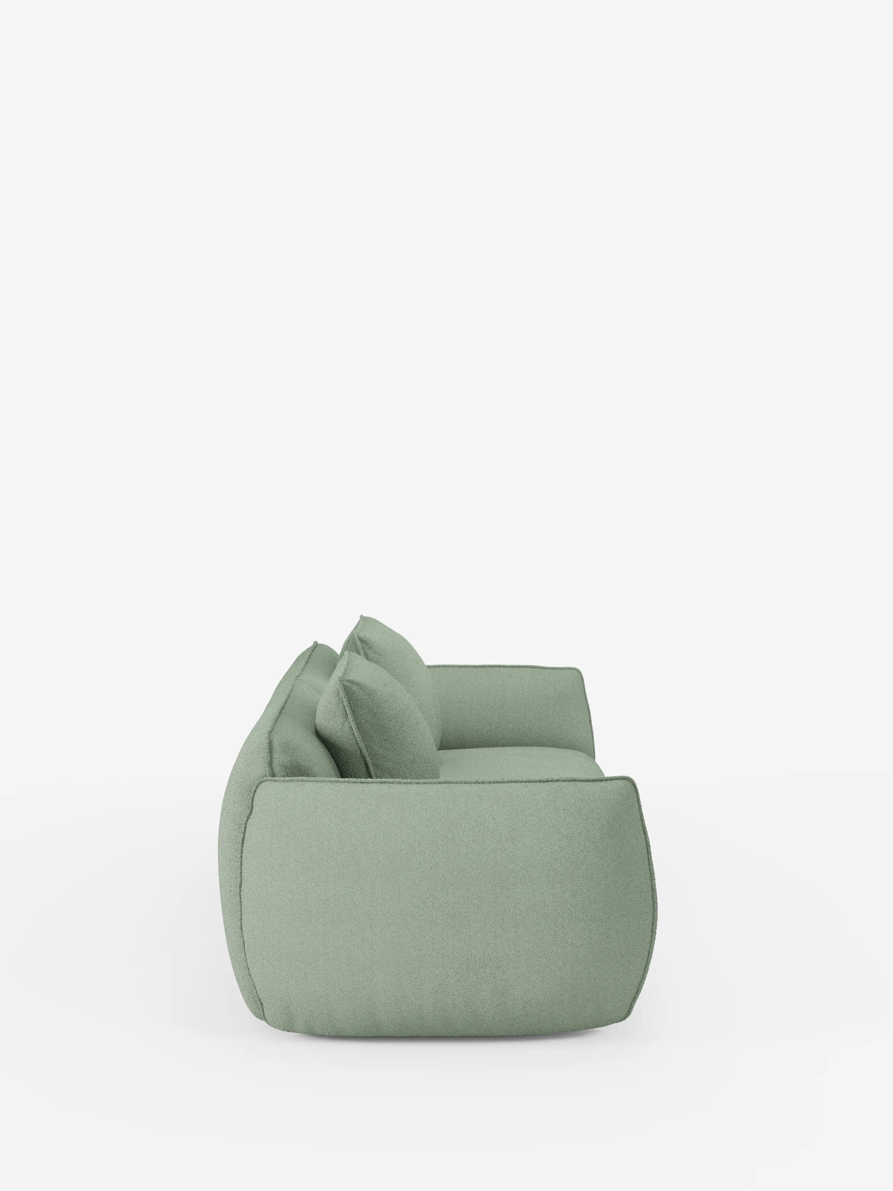 Vista laterale di un moderno divano Nimbus a 3 posti, modulare e componibile, da 250 cm, di colore verde chiaro, di divitt.sbs, rivestito in tessuto T33 effetto cotone, sfoderabile e antimacchia, con due cuscini dello schienale, su uno sfondo bianco a tinta unita. Il divano presenta una forma bassa e squadrata e bordi morbidi e arrotondati che gli conferiscono un aspetto accogliente e contemporaneo.