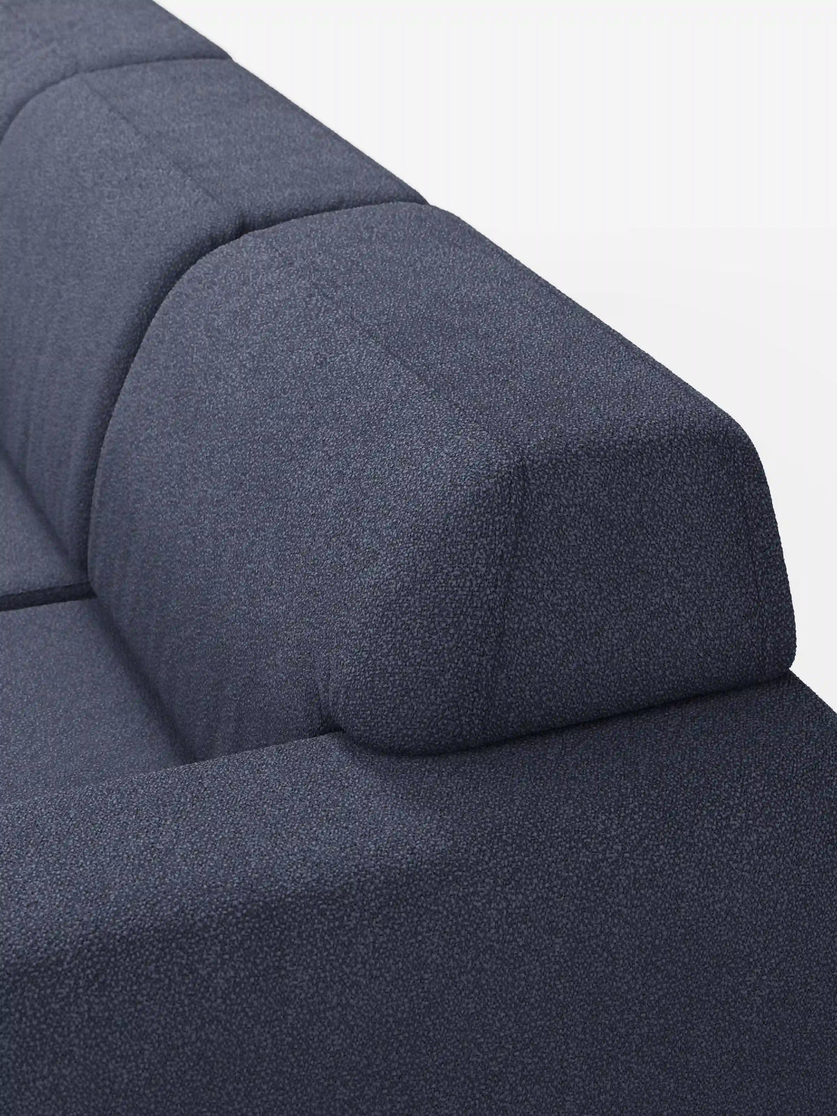 Un primo piano dell’Orbit Divano angolare con penisola reversibile e tutte le sedute allungabili in tessuto smacchiabile effetto cotone T33 di divitt.sbs mette in risalto il suo tessuto testurizzato, di colore blu scuro, resistente alle macchie ed effetto cotone, le linee pulite e lo schienale angolato. L'immagine mette in risalto il bracciolo e lo schienale su uno sfondo bianco a tinta unita.