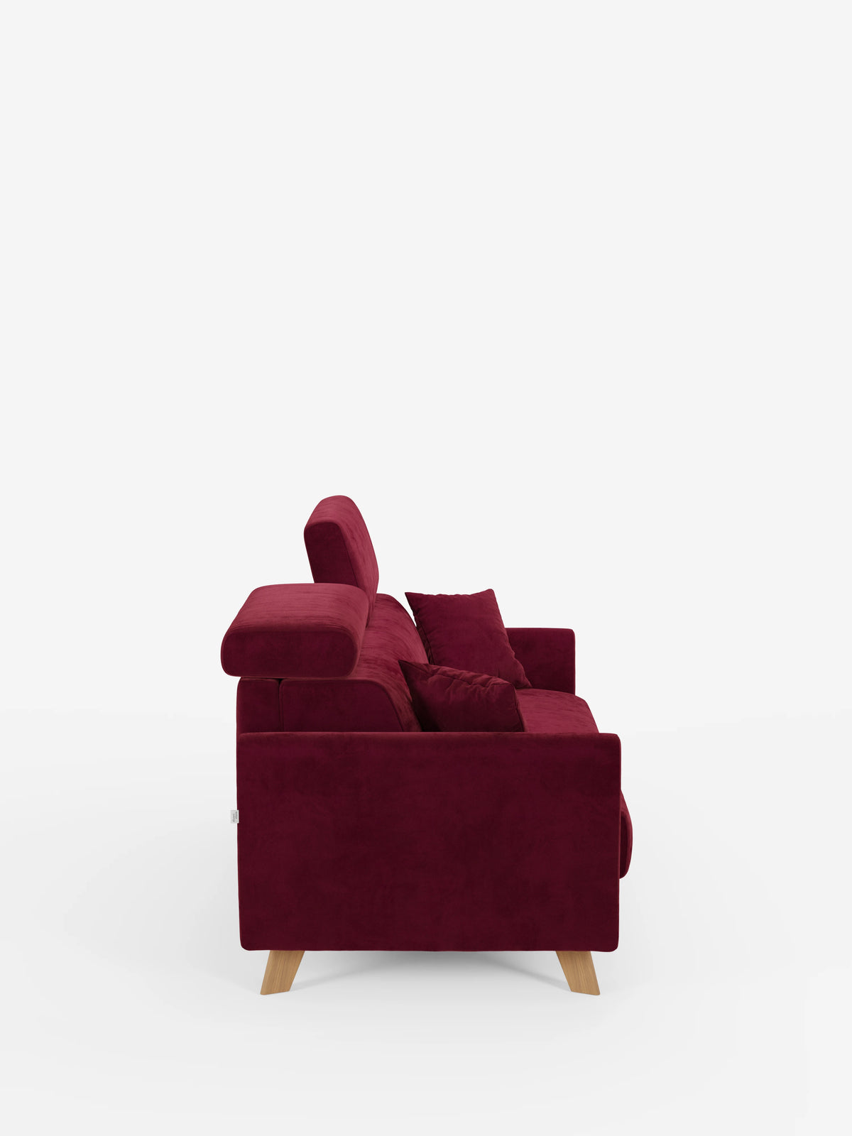 Una vista laterale del divano letto Francy con poggiatesta regolabili di divitt.sbs, rivestito in tessuto T30 rosso intenso, elegante e resistente alle macchie. Questo moderno divano a tre posti presenta gambe in legno chiaro, rivestimenti completamente sfoderabili, poggiatesta regolabili e due cuscini abbinati in rosso, il tutto su uno sfondo bianco a tinta unita.