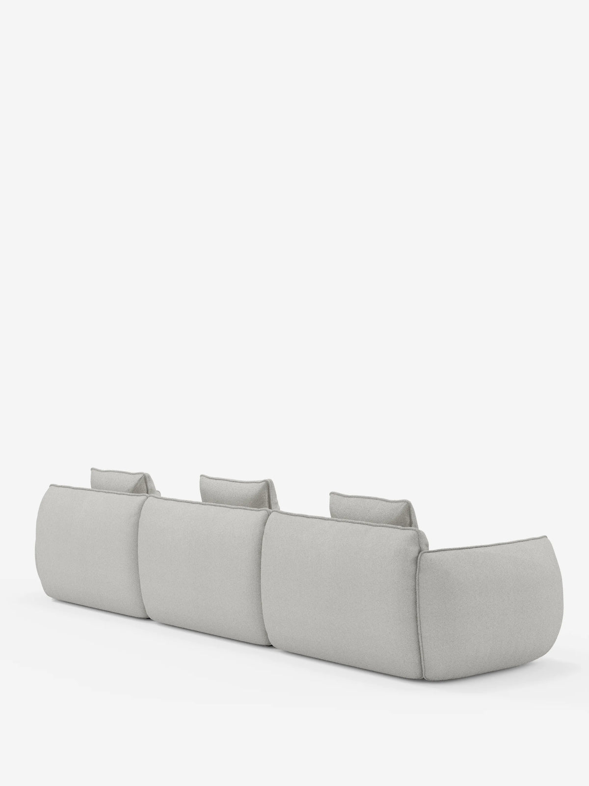 Il divano modulare a 3 posti Nimbus, realizzabile in morbido tessuto smacchiabile effetto cotone T33 di divitt.sbs, è ripreso da dietro, mettendo in risalto il suo design moderno in grigio chiaro con angoli arrotondati, ampi braccioli e tre poggiatesta individuali, il tutto su uno sfondo bianco a tinta unita.
