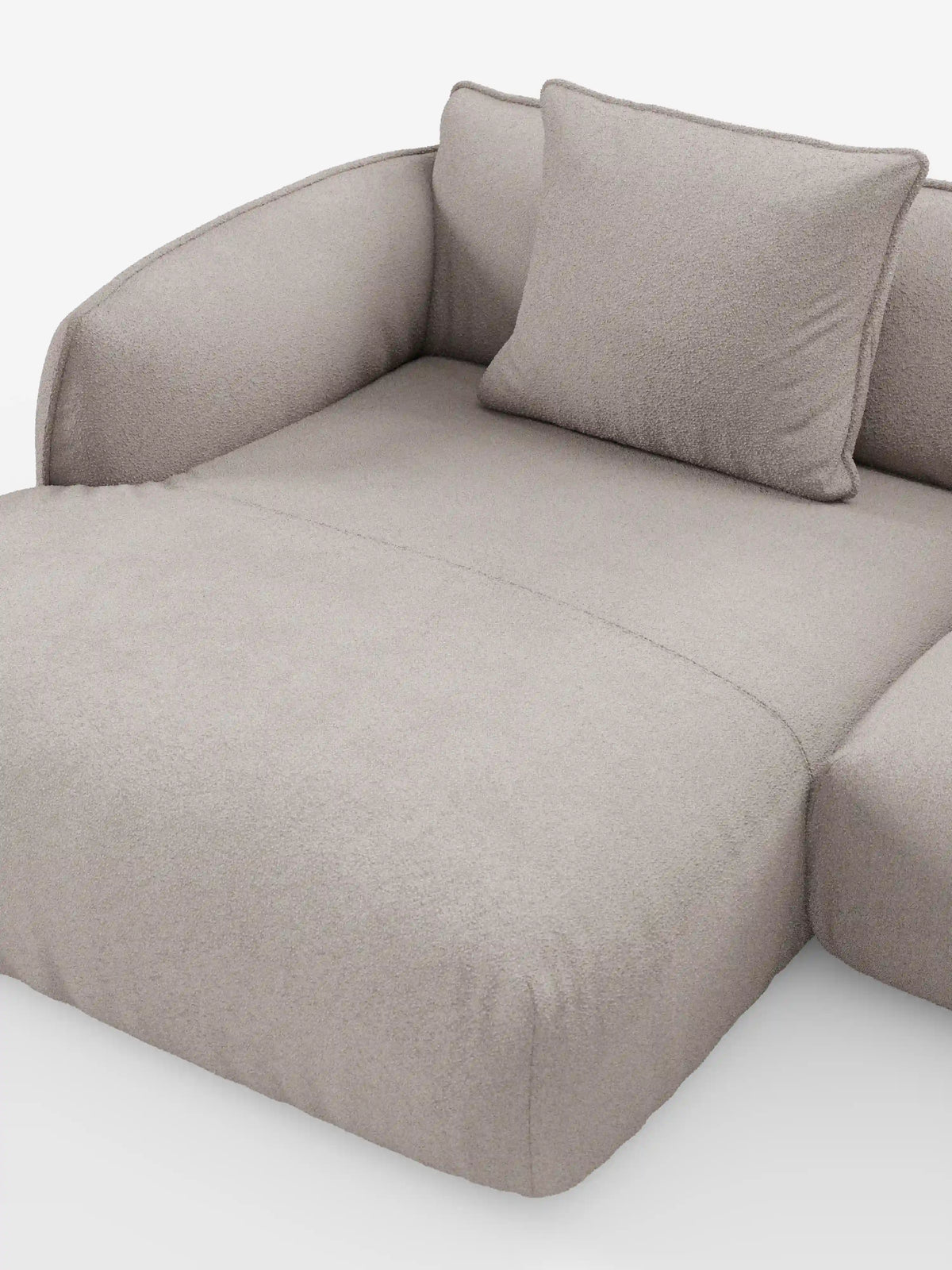 Un divano angolare panoramico componibile Nimbus in stile contemporaneo con penisola e angolo in tessuto smacchiabile T33 di divitt.sbs, rivestito in tessuto beige chiaro con una finitura morbida e testurizzata. Questo divano Made in Italy presenta sedute profonde, braccioli arrotondati ed è corredato da un unico cuscino quadrato coordinato, il tutto presentato su uno sfondo bianco a tinta unita.