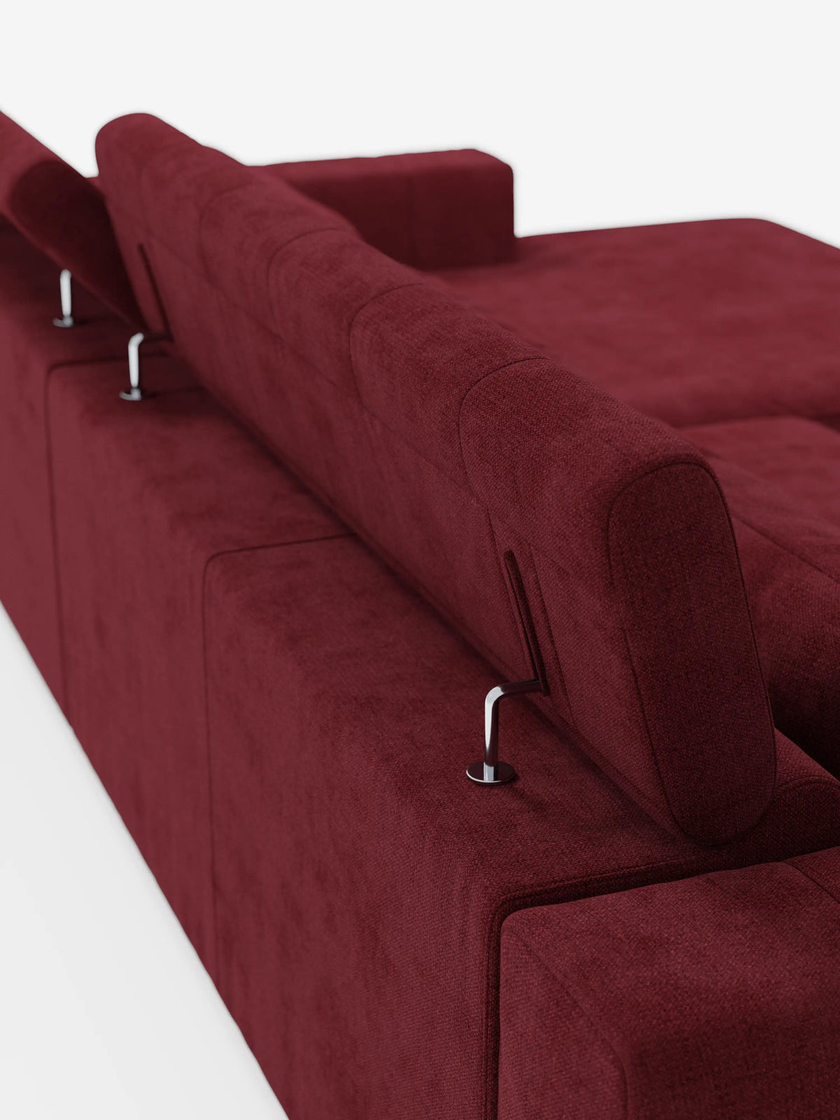 Vista posteriore del divano angolare dorico con penisola e sedute allungabili con funzione relax elettrica di divitt.sbs, rivestito in tessuto T23 color bordeaux scuro facile da pulire, dotato di poggiatesta regolabili sostenuti da eleganti aste metalliche. Il divano presenta linee pulite e rettangolari e un aspetto morbido e materico, che risalta sullo sfondo bianco a tinta unita.