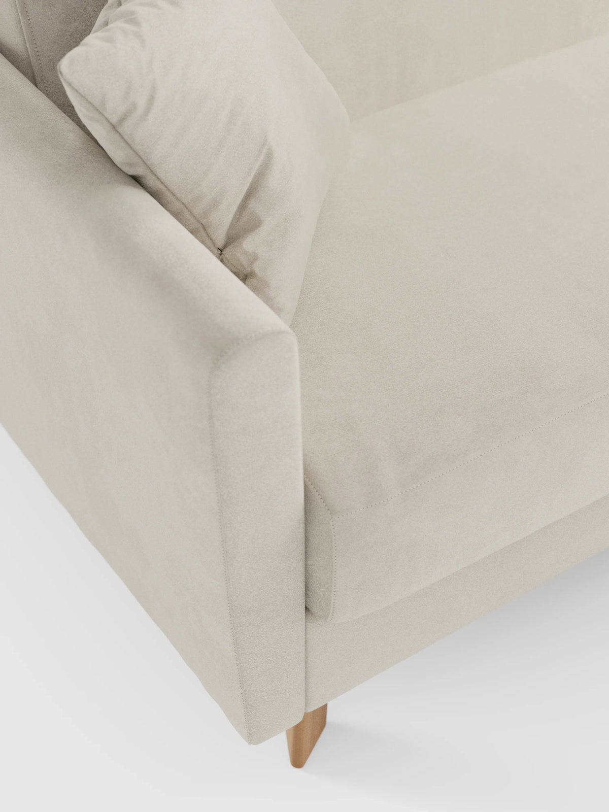 Un primo piano del divano letto Francy con poggiatesta regolabili di divitt.sbs, rivestito in elegante tessuto T30 beige resistente alle macchie. Questo moderno divano a due posti è dotato di rivestimenti completamente sfoderabili, seduta, schienale e braccioli imbottiti. Un cuscino quadrato abbinato è posizionato in un angolo, mentre il divano poggia su gambe corte e angolate in legno su uno sfondo bianco.