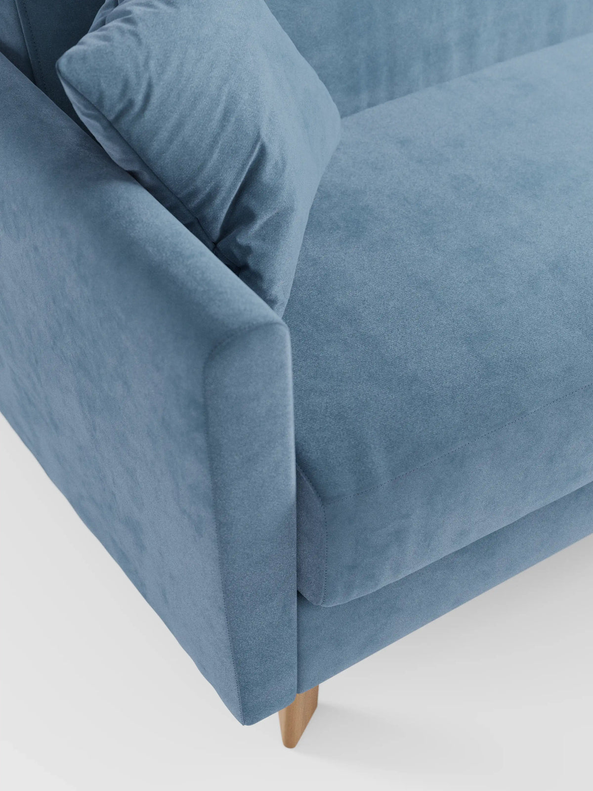 Un primo piano del divano letto Francy con poggiatesta regolabili di divitt.sbs in azzurro, con bracciolo sinistro, cuscino di seduta e un cuscino coordinato. Questo moderno divano letto poggia su gambe in legno su uno sfondo bianco, mettendo in risalto il suo elegante tessuto T30 smacchiabile dalla texture morbida, completamente sfoderabile.