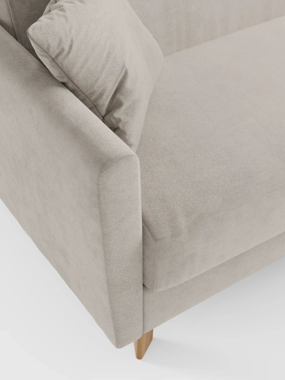 Primo piano del divano letto Francy con poggiatesta regolabili di divitt.sbs, rivestito in elegante tessuto T30 resistente alle macchie. L'immagine mette in risalto il bracciolo angolato di questo moderno divano beige, con cuscini dello schienale e della seduta abbinati. Questo versatile divano a due posti è dotato di rivestimenti completamente sfoderabili e poggia su gambe in legno chiaro su uno sfondo bianco a tinta unita. Il design complessivo è minimalista e pulito.