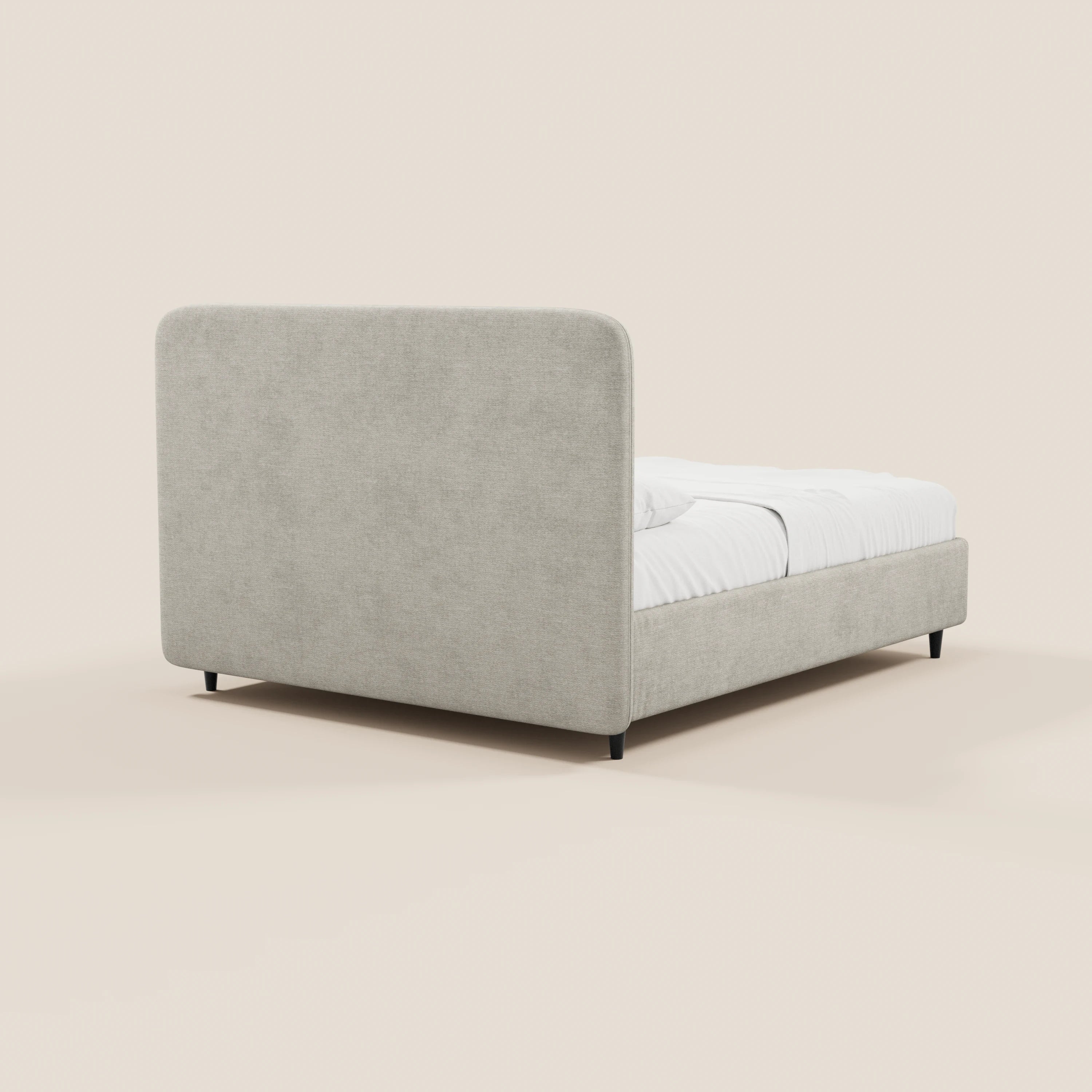 Il letto imbottito KAELOS minimal di Letti.store presenta una testiera alta e arrotondata in ciniglia grigio chiaro con pannelli laterali, biancheria da letto bianca, piedini alti neri e un vano contenitore. Immagine che lo ritrae di retro e di profilo su uno sfondo beige chiaro.