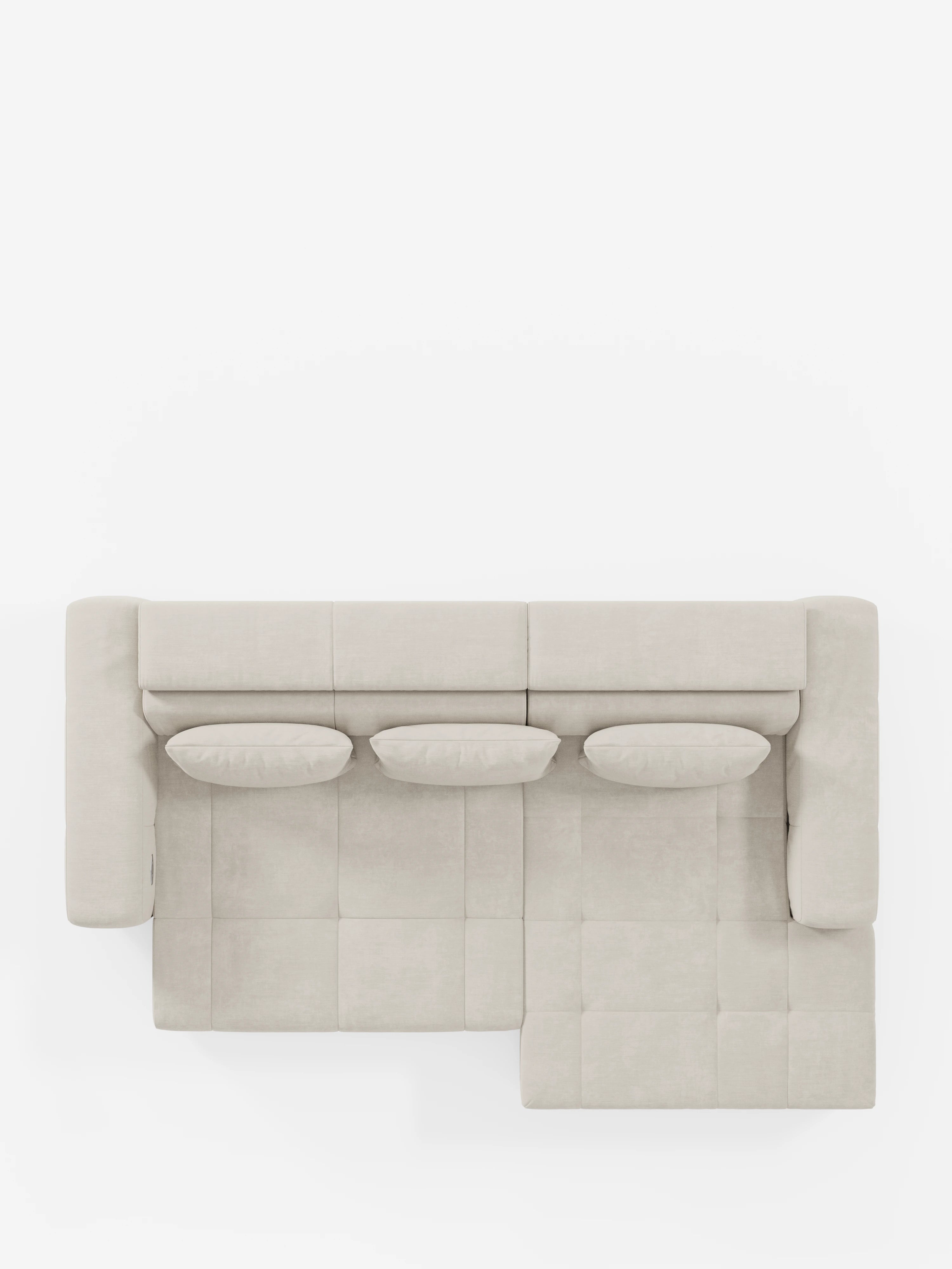 Vista dall'alto del divano angolare Monarch con penisola e funzione Relax Elettrico per l'allungamento delle sedute di divitt.sbs, rivestito in morbido tessuto T31 resistente alle macchie. Questo divano a L color beige chiaro è dotato di tre cuscini ovali coordinati e poggiatesta regolabili. La chaise longue si trova sul lato destro.